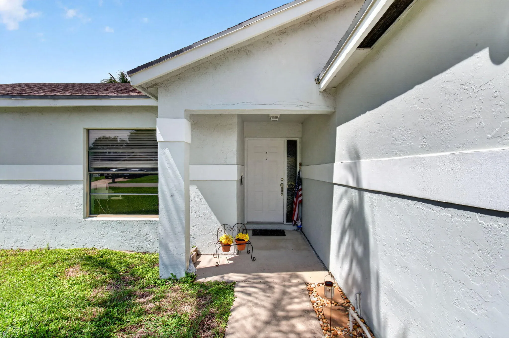 Front entry with covered porch, white door, and textured exterior finish