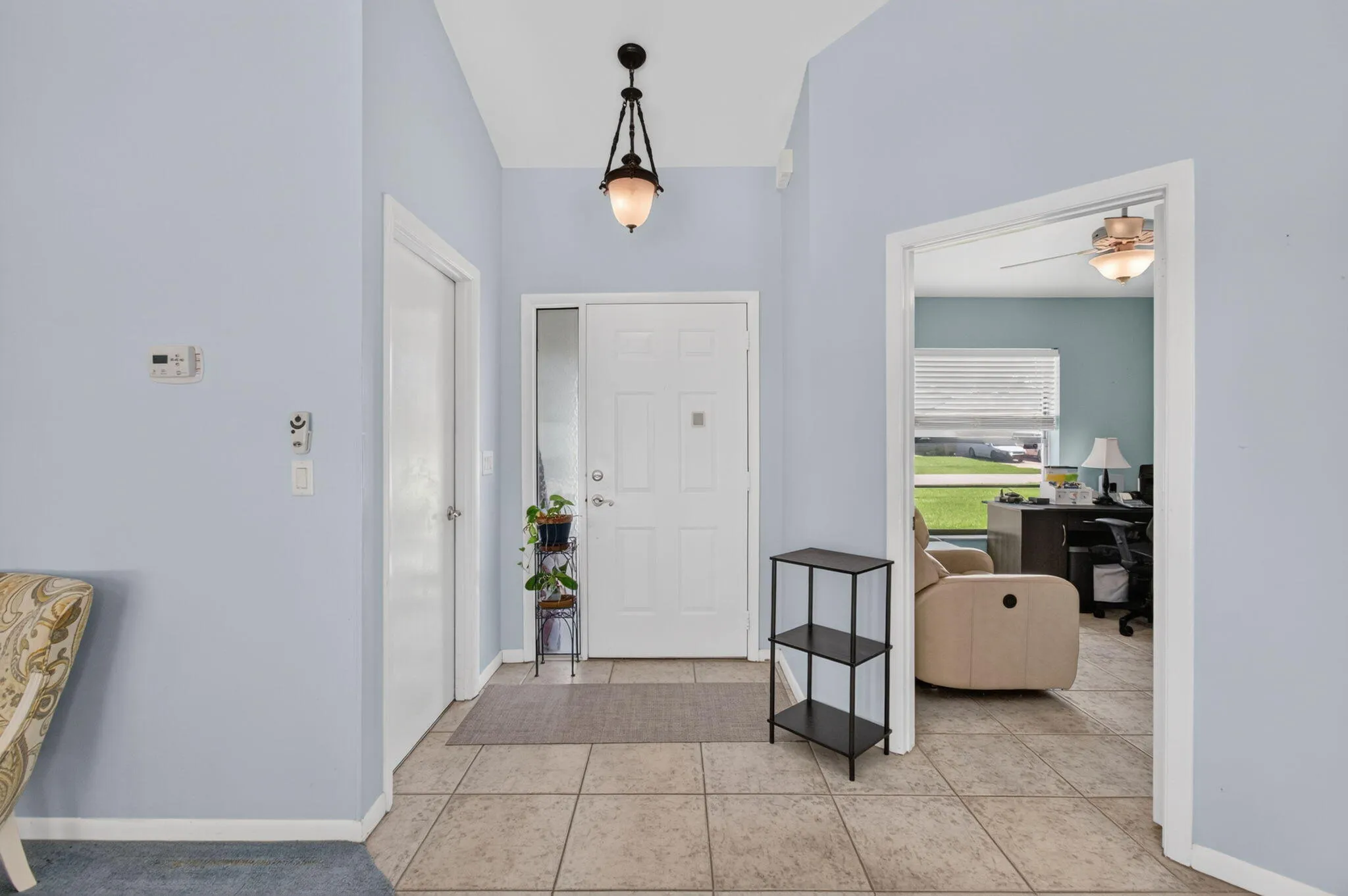 Entryway featuring tiled flooring, a vaulted ceiling, and an overhead pendant light fixture