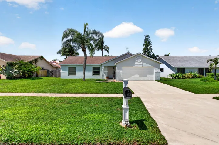 Single-story residence featuring a two-car garage, concrete driveway, and mature landscaping