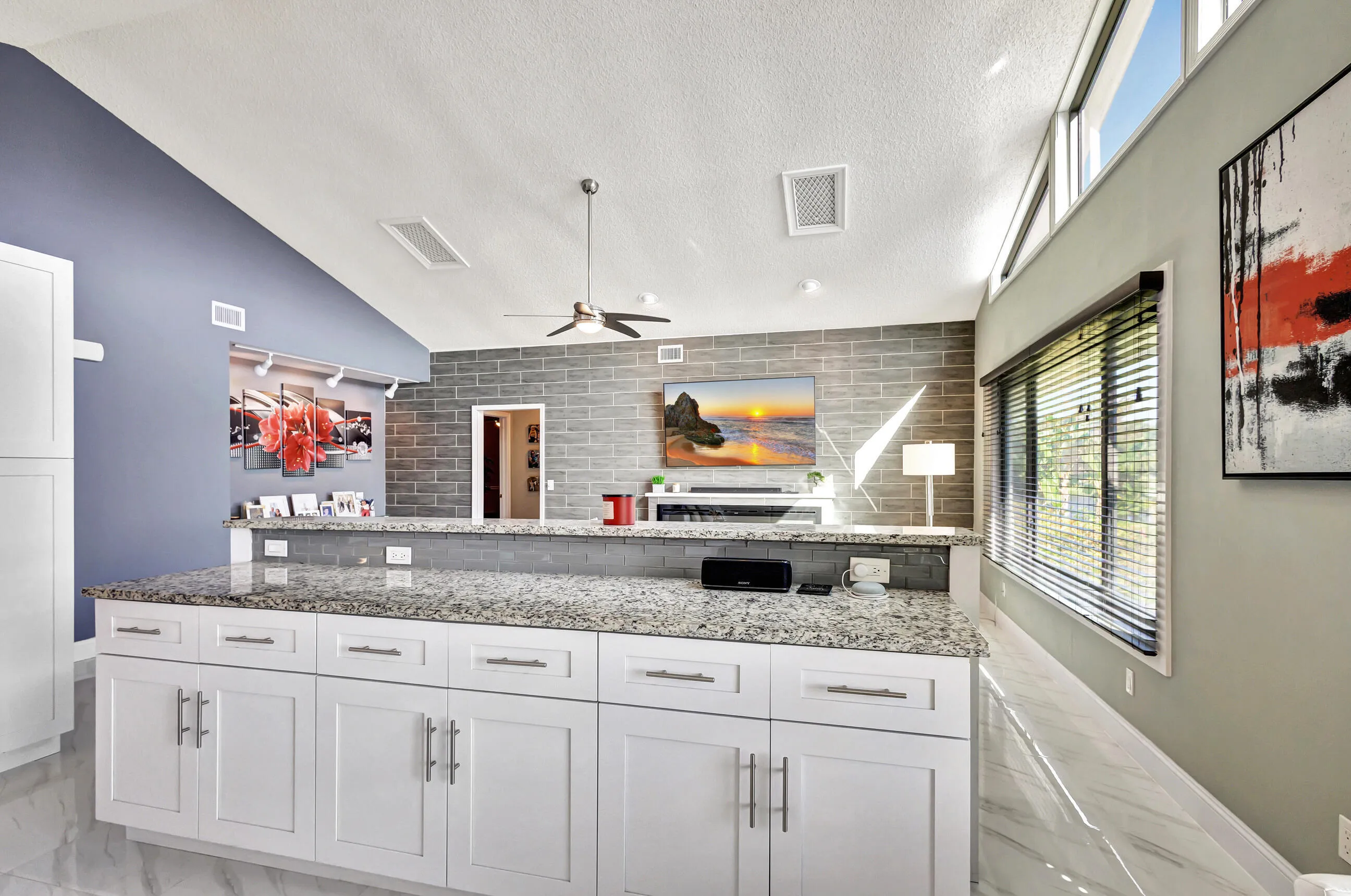 Elongated kitchen island featuring white cabinetry and a speckled countertop