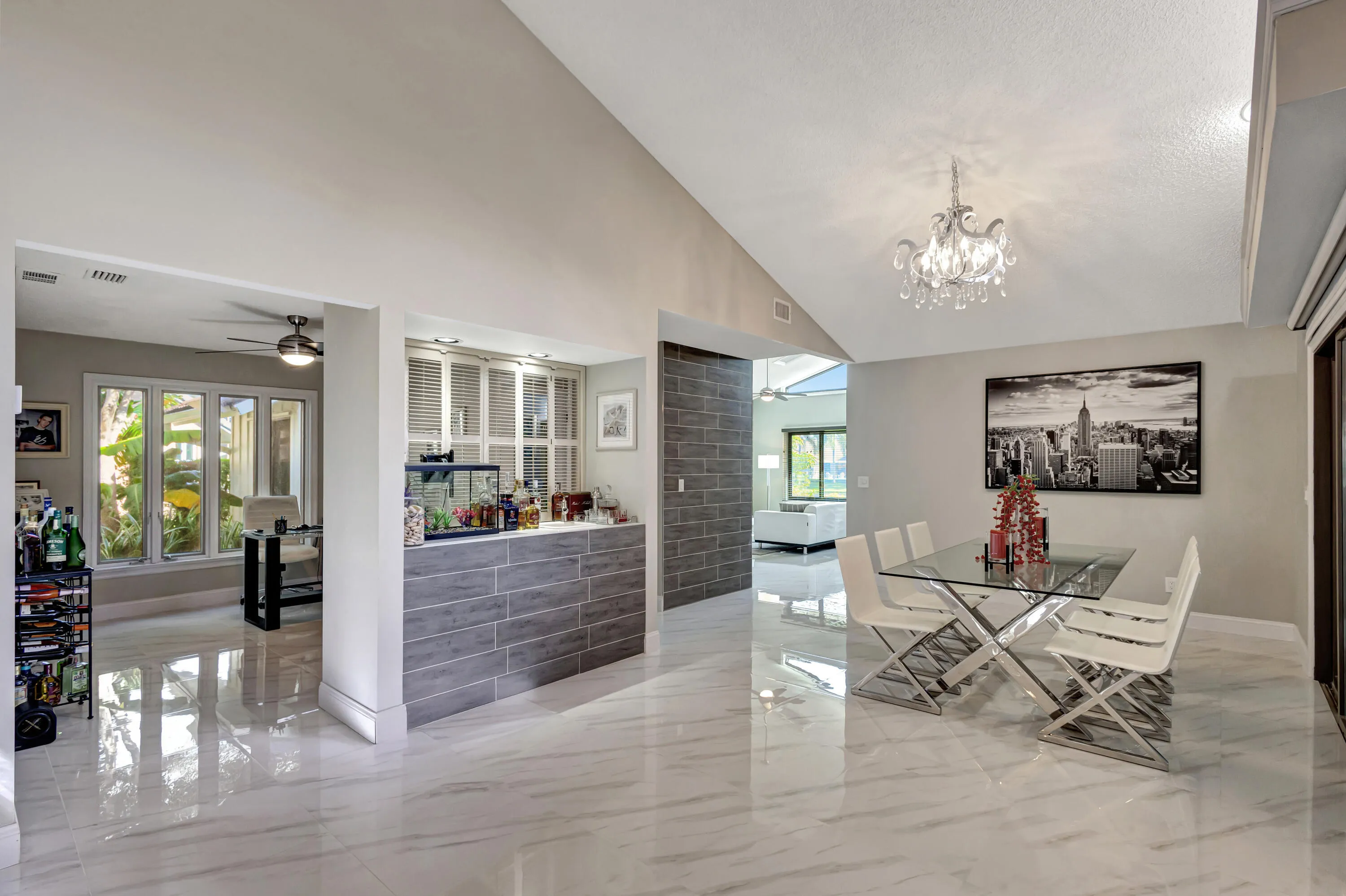 Vaulted ceilings with recessed lighting, large format marble-look tile flooring, built-in shelving, and a decorative chandelier