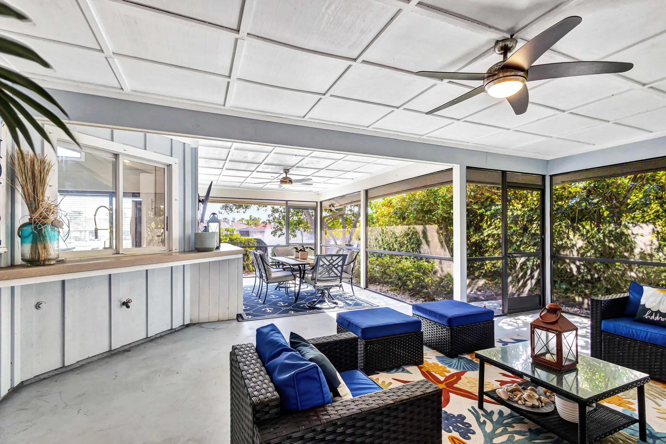 Screened lanai with a coffered ceiling, multiple ceiling fans, and a pass-through window to the interior