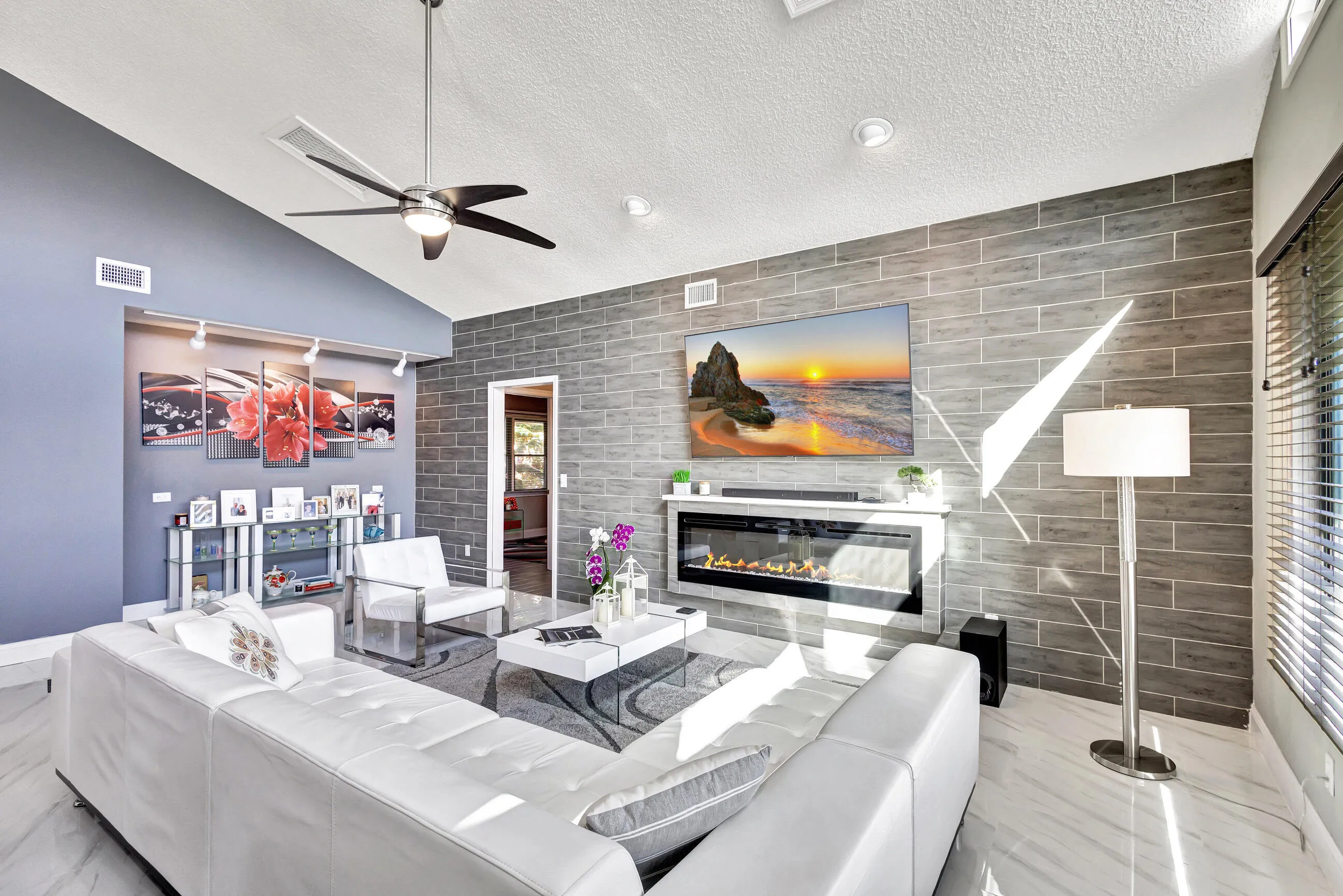 Vaulted ceiling, ceiling fan, recessed lighting, tile flooring, and a fireplace with a stone-finish accent wall