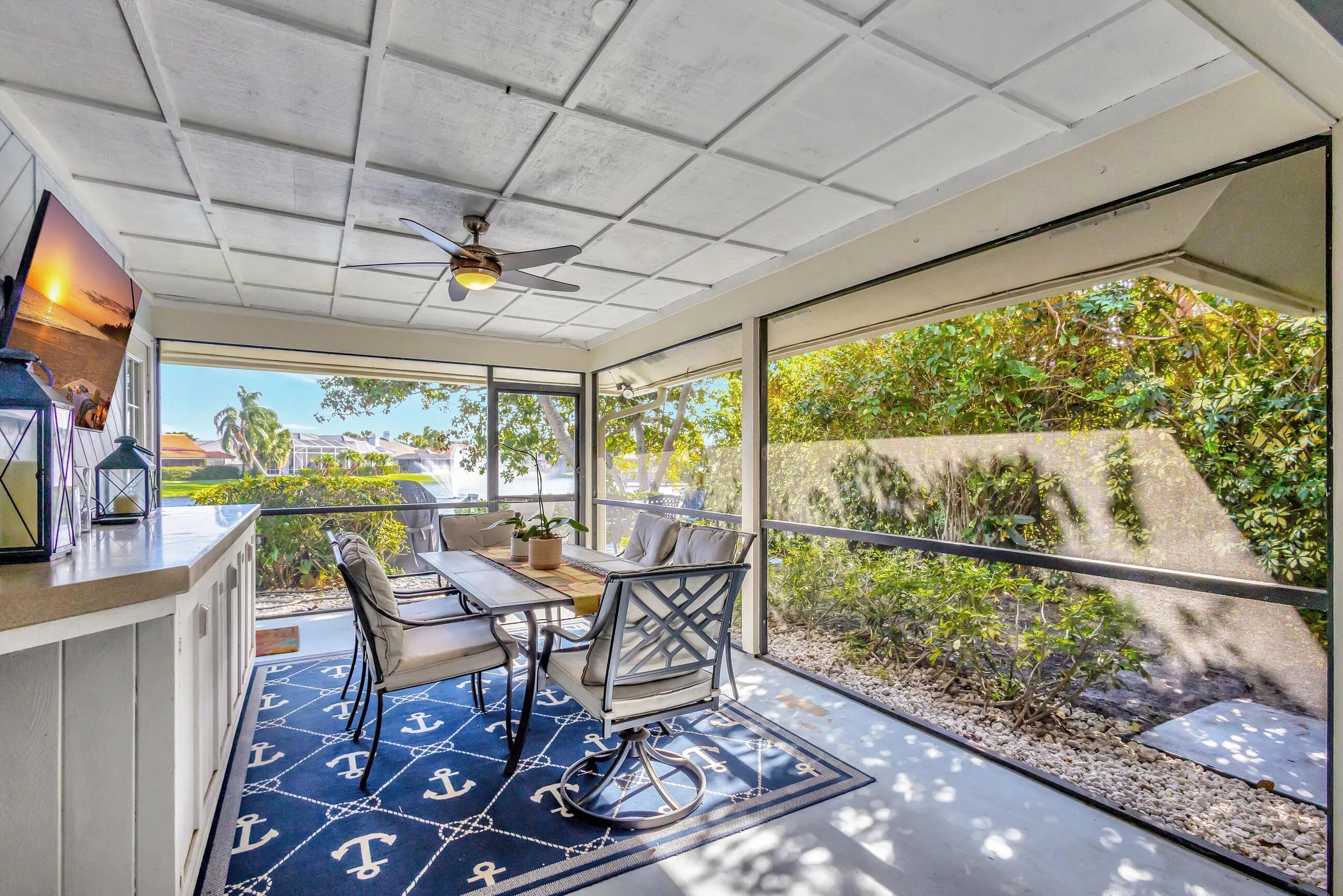 Screened outdoor living area featuring a coffered ceiling, built-in bar with counter space, and a ceiling fan