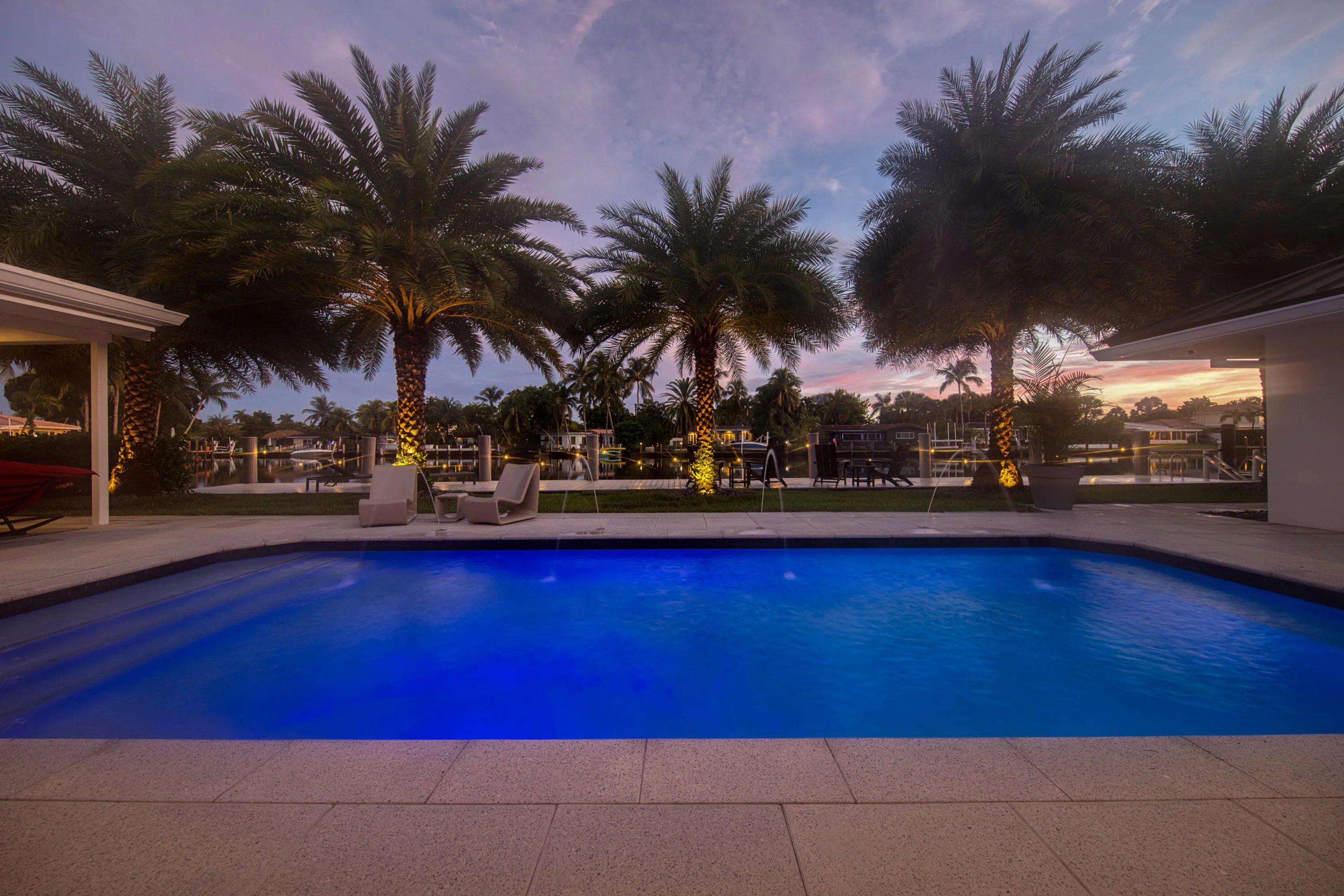 The pool, palms, dock and waterfront view at sunset