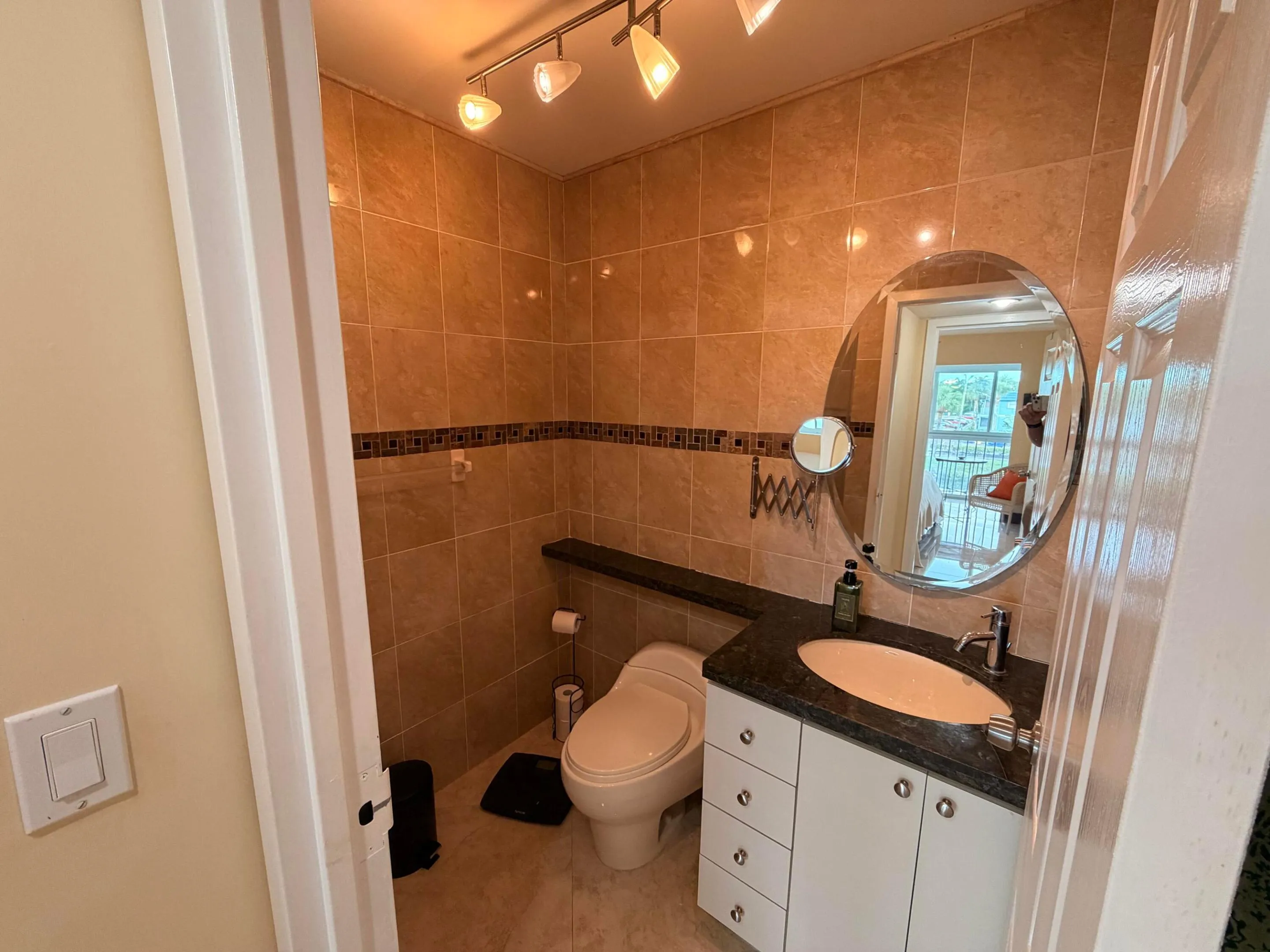 Tiled bathroom featuring a vanity with an integrated sink and dark countertop, an oval mirror, and a track lighting fixture