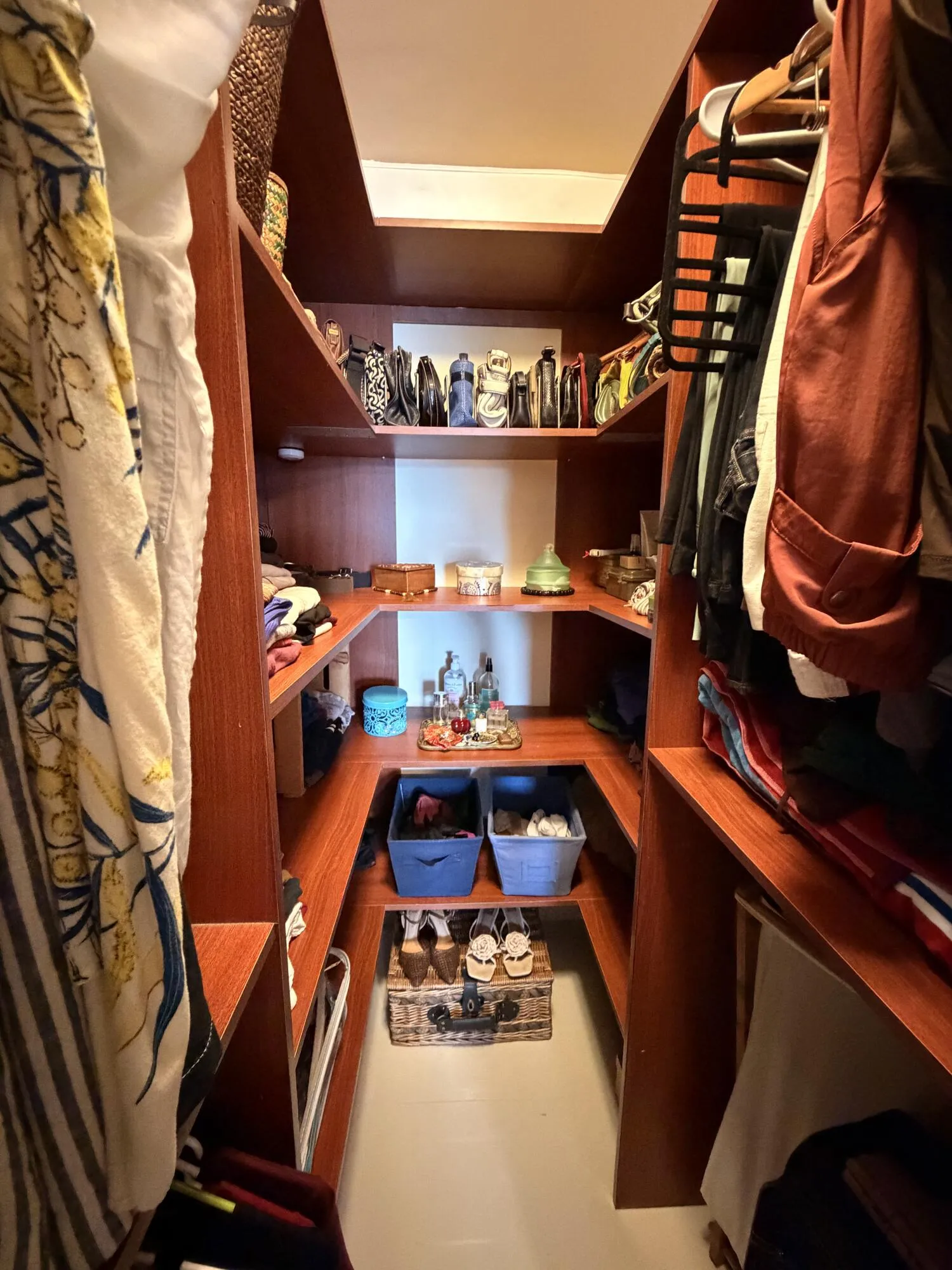 Built-in wood-finish shelving with multiple levels of storage and hanging rods