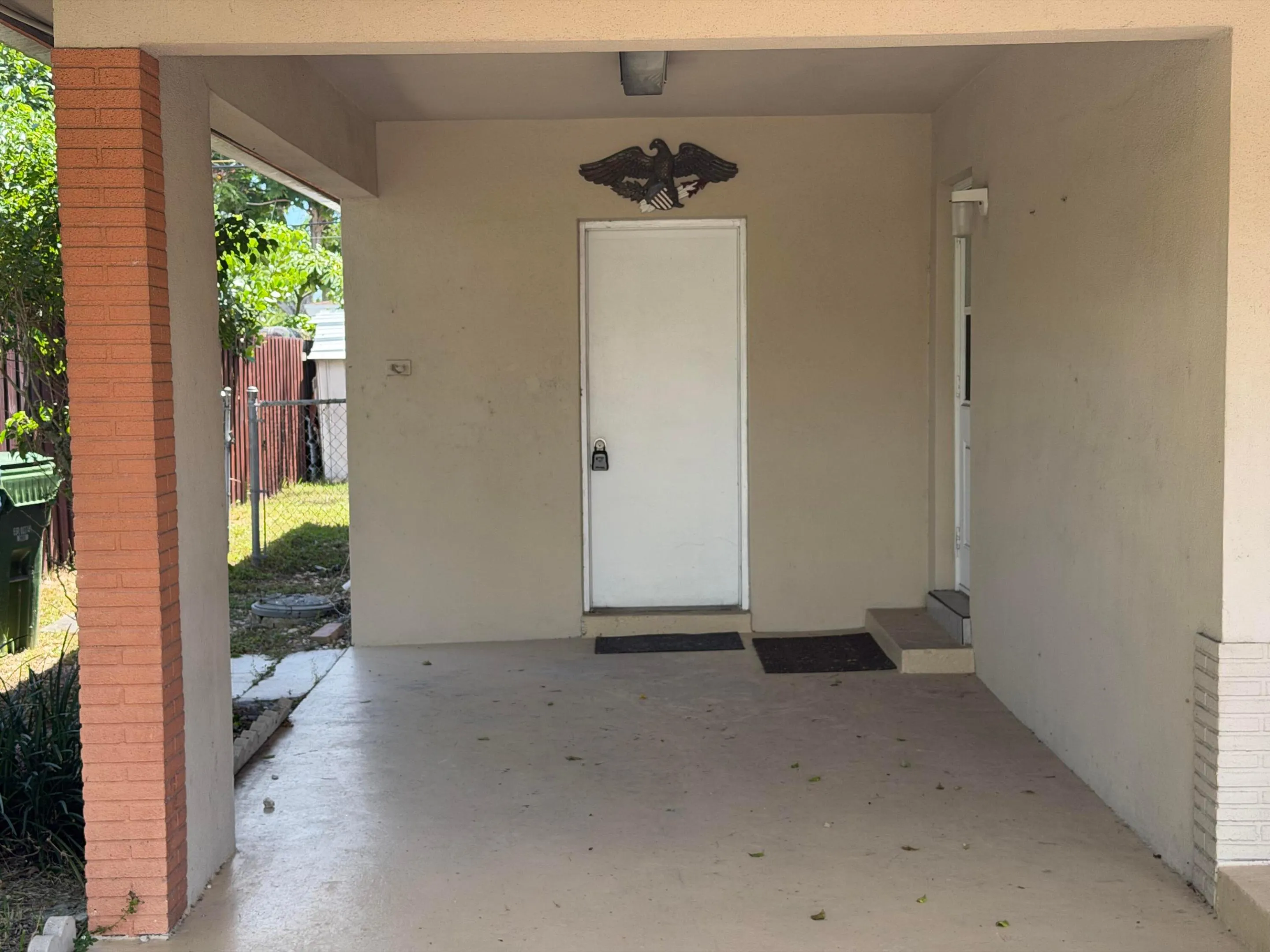 Covered entryway with painted concrete flooring, a brick column, and a white entry door