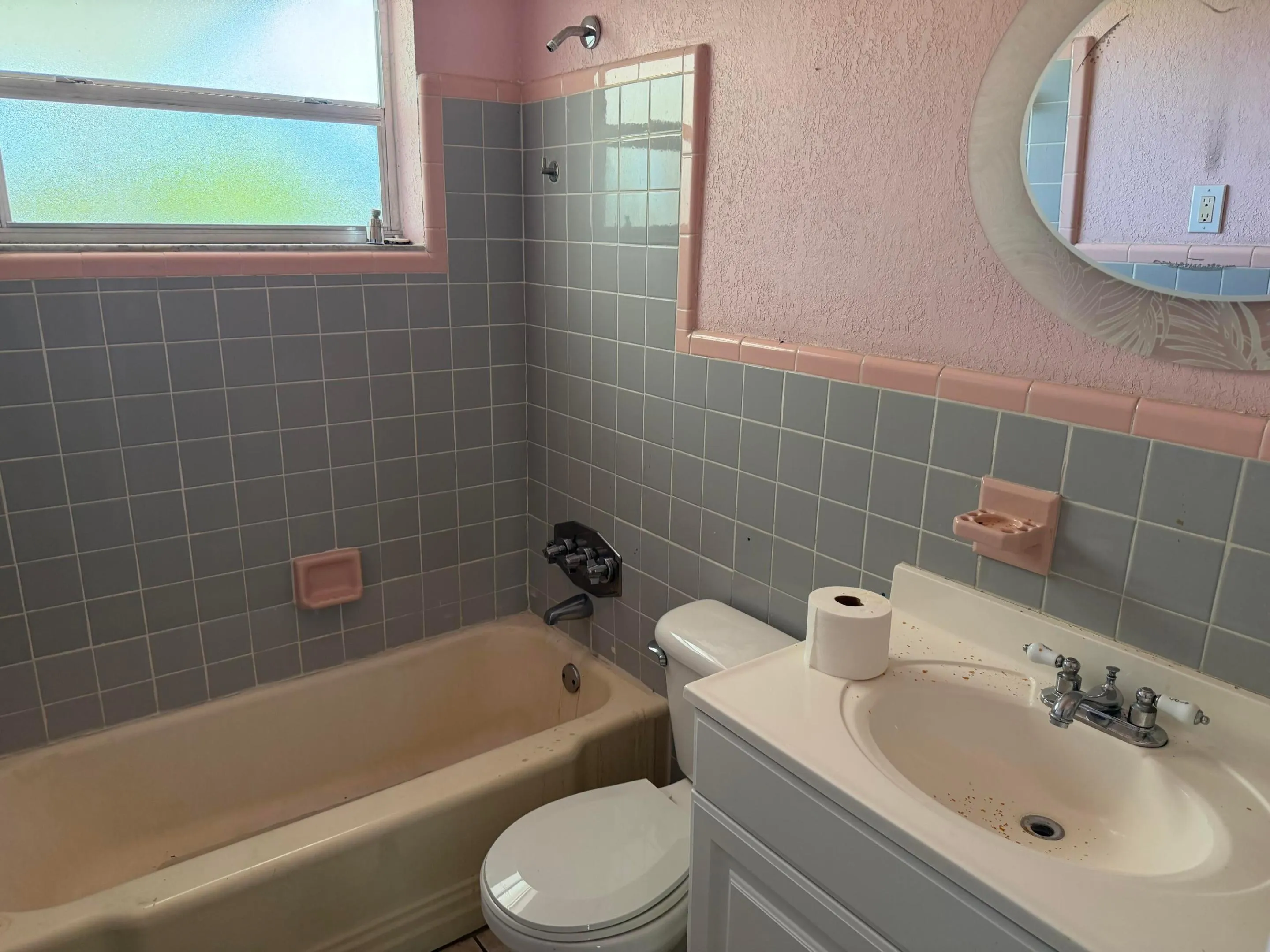 Hall Bathroom featuring a built-in tub, tiled shower surround, window with privacy glass, and a vanity with an integrated sink
