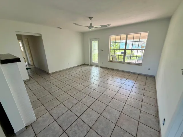 Ceramic tile flooring, white painted walls, ceiling fan, multiple windows for ample light, and a glass-paneled exterior door