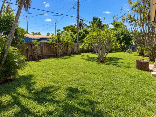 Expansive grassy yard with a privacy fence and mature landscaping