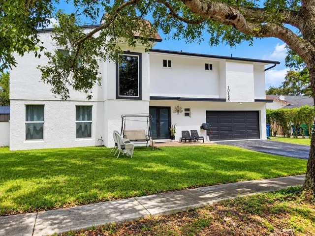 Contemporary two-story exterior with a two-car garage, prominent large window, and light-colored stucco finish