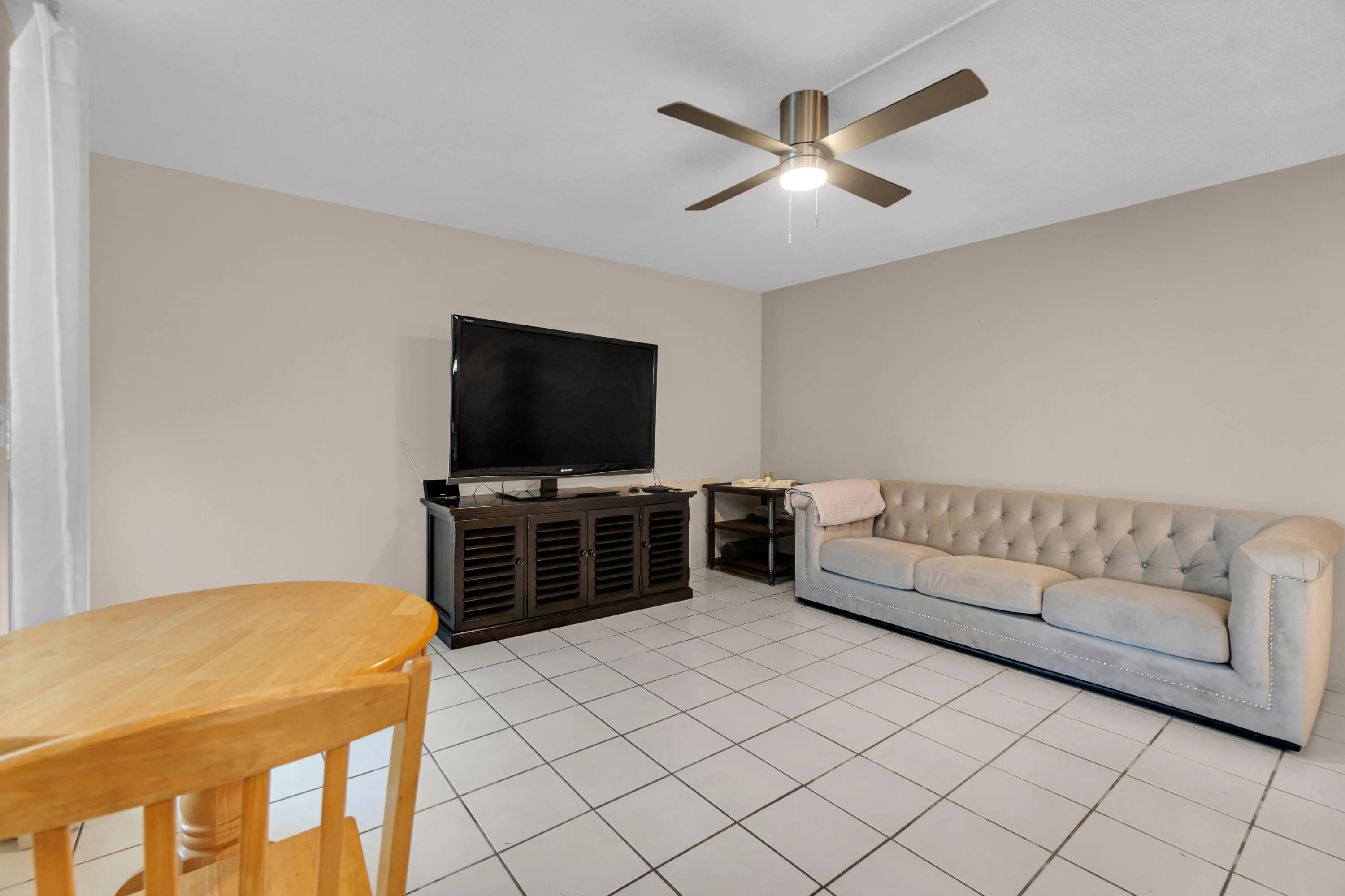 Light-colored tile flooring, neutral wall paint, and a ceiling fan with integrated lighting