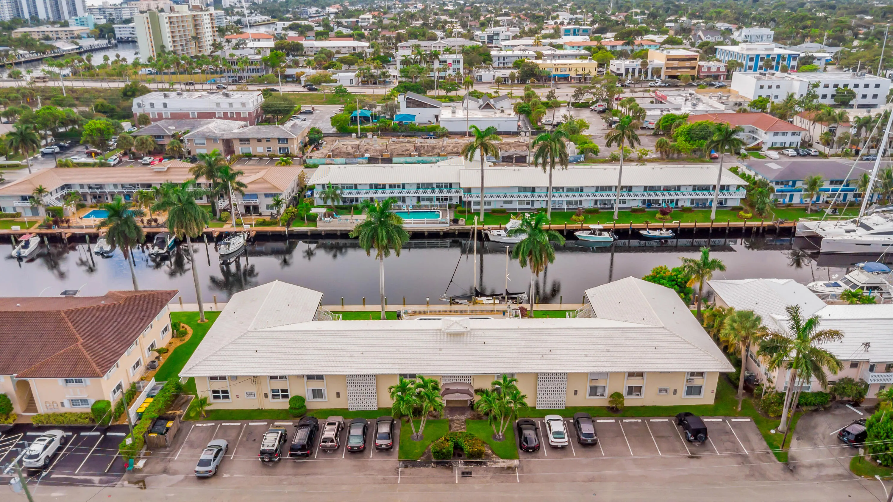 Waterfront property featuring multiple buildings, abundant palm trees, and dedicated parking areas