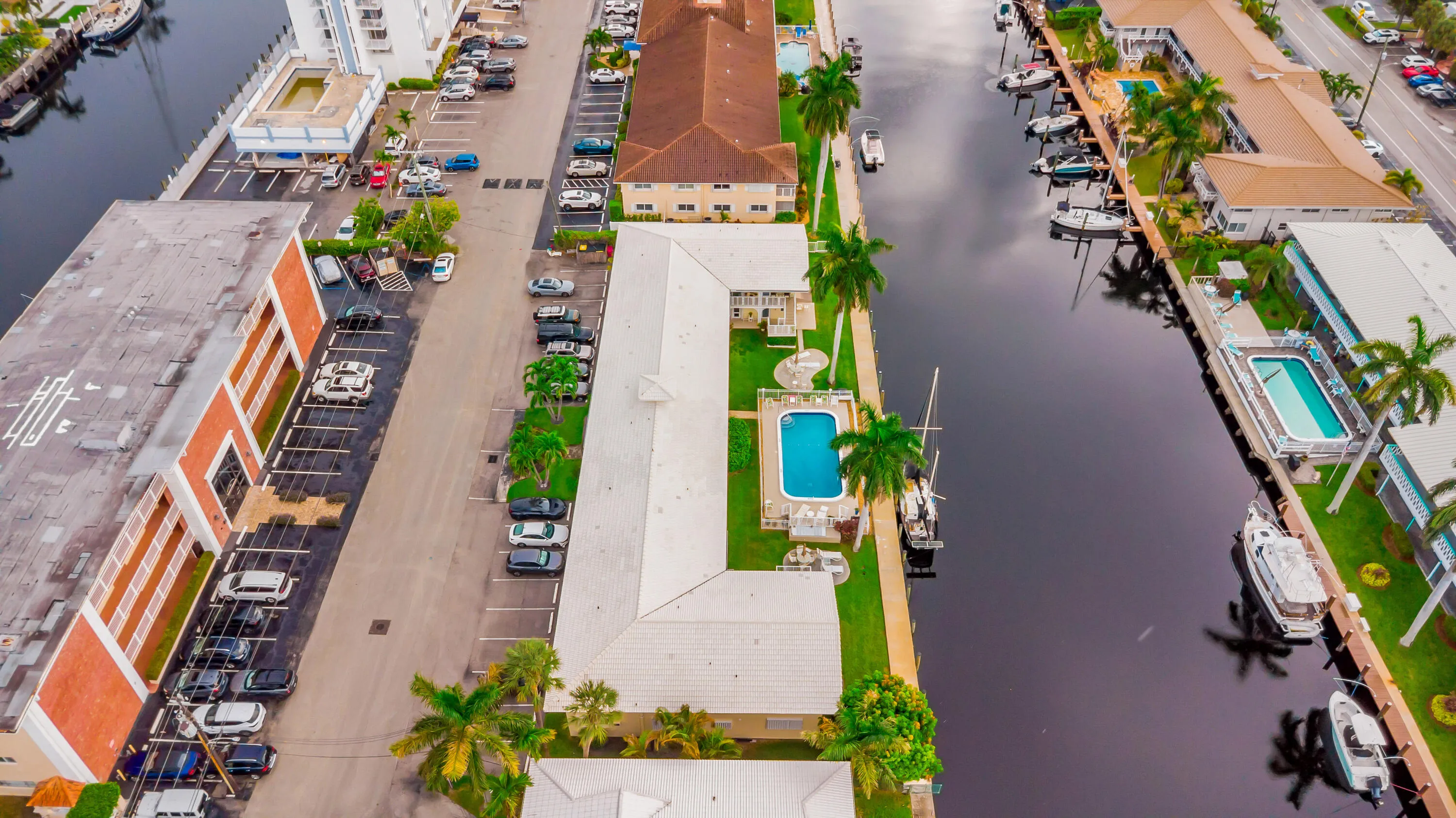 Waterfront property featuring a private boat dock, outdoor swimming pool, and mature palm trees