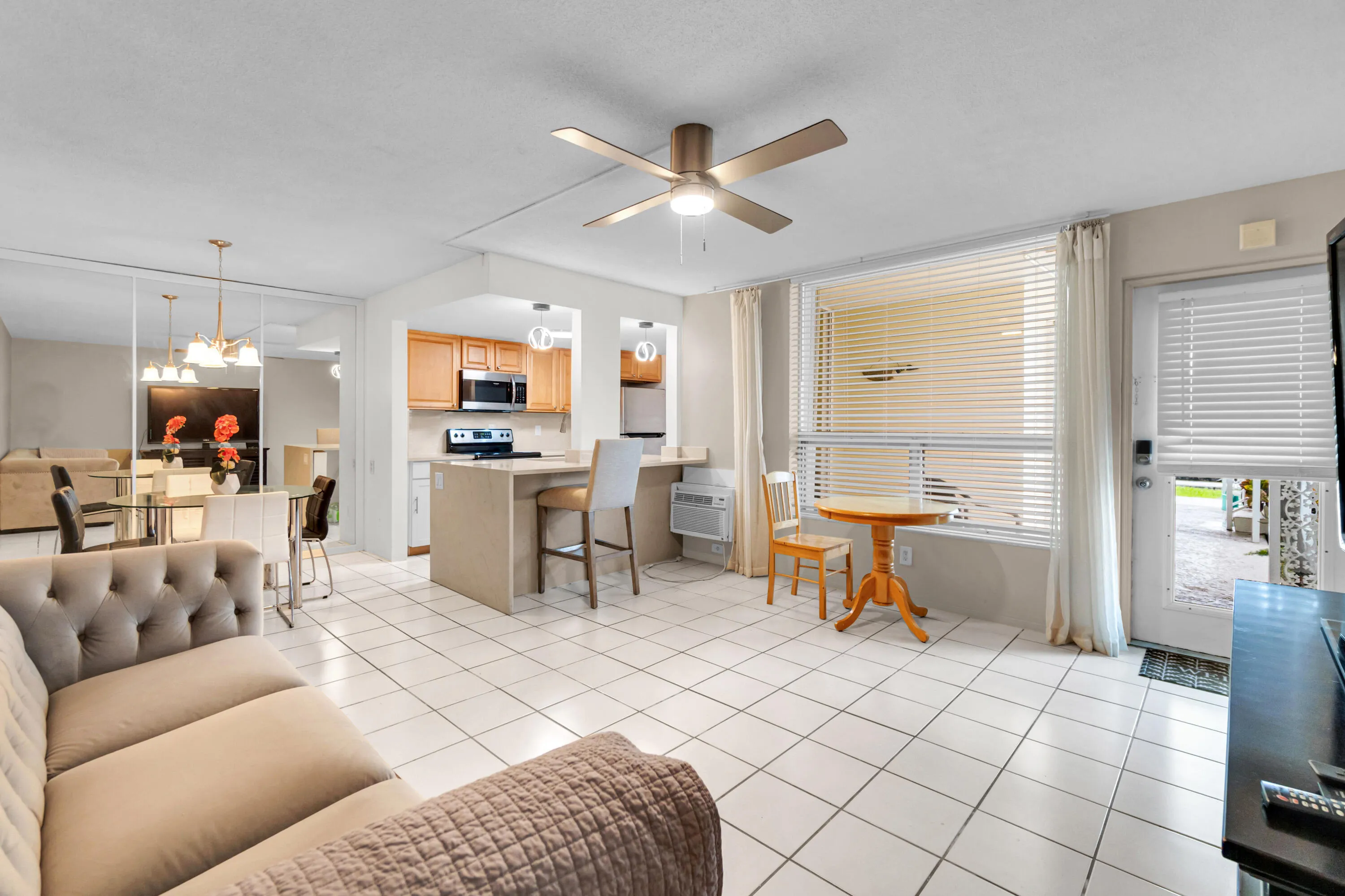 Open concept living space featuring tile flooring, a ceiling fan, and a kitchen with wood cabinetry