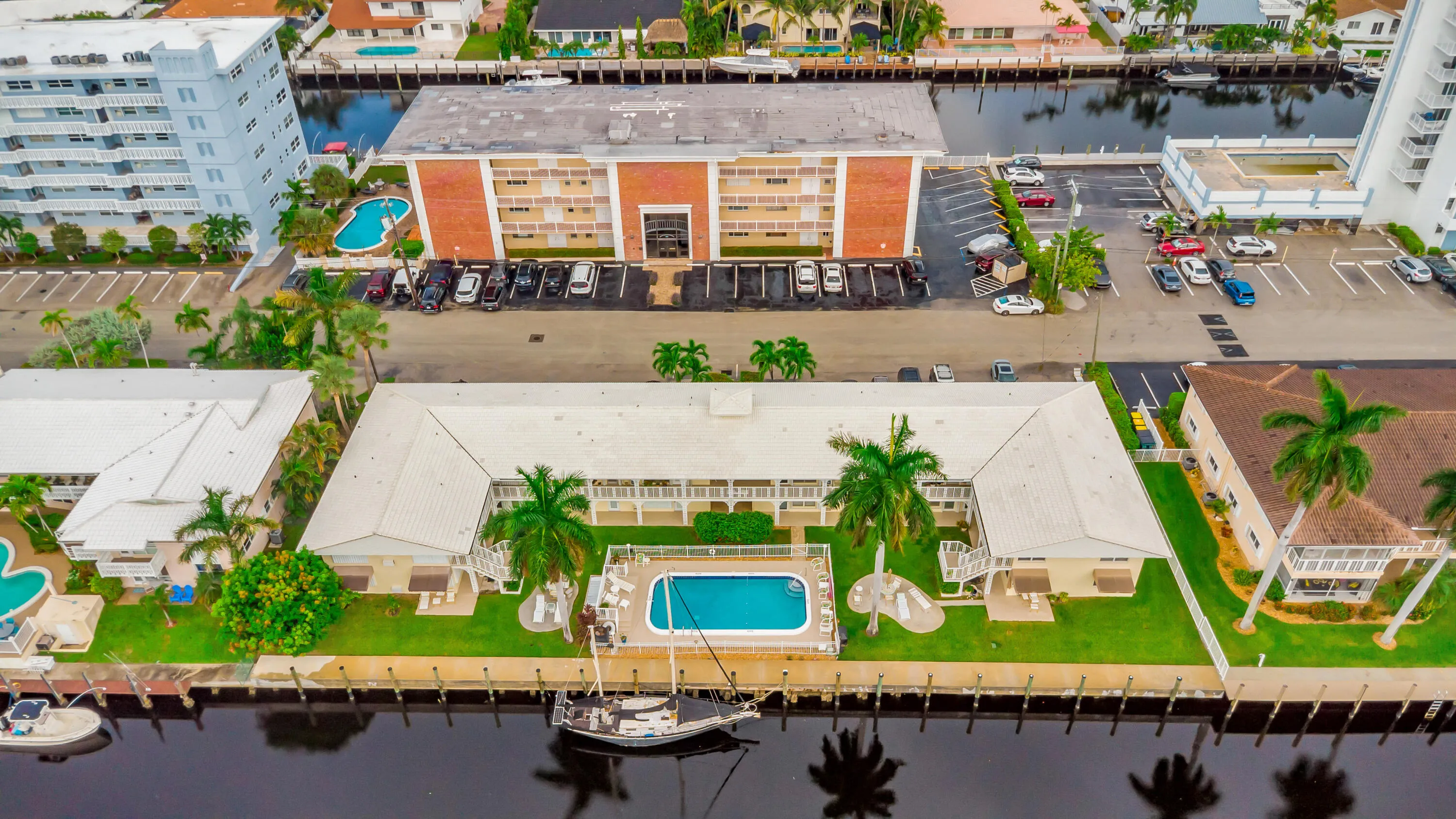 Waterfront property featuring a private swimming pool, surrounding green space, and mature palm trees