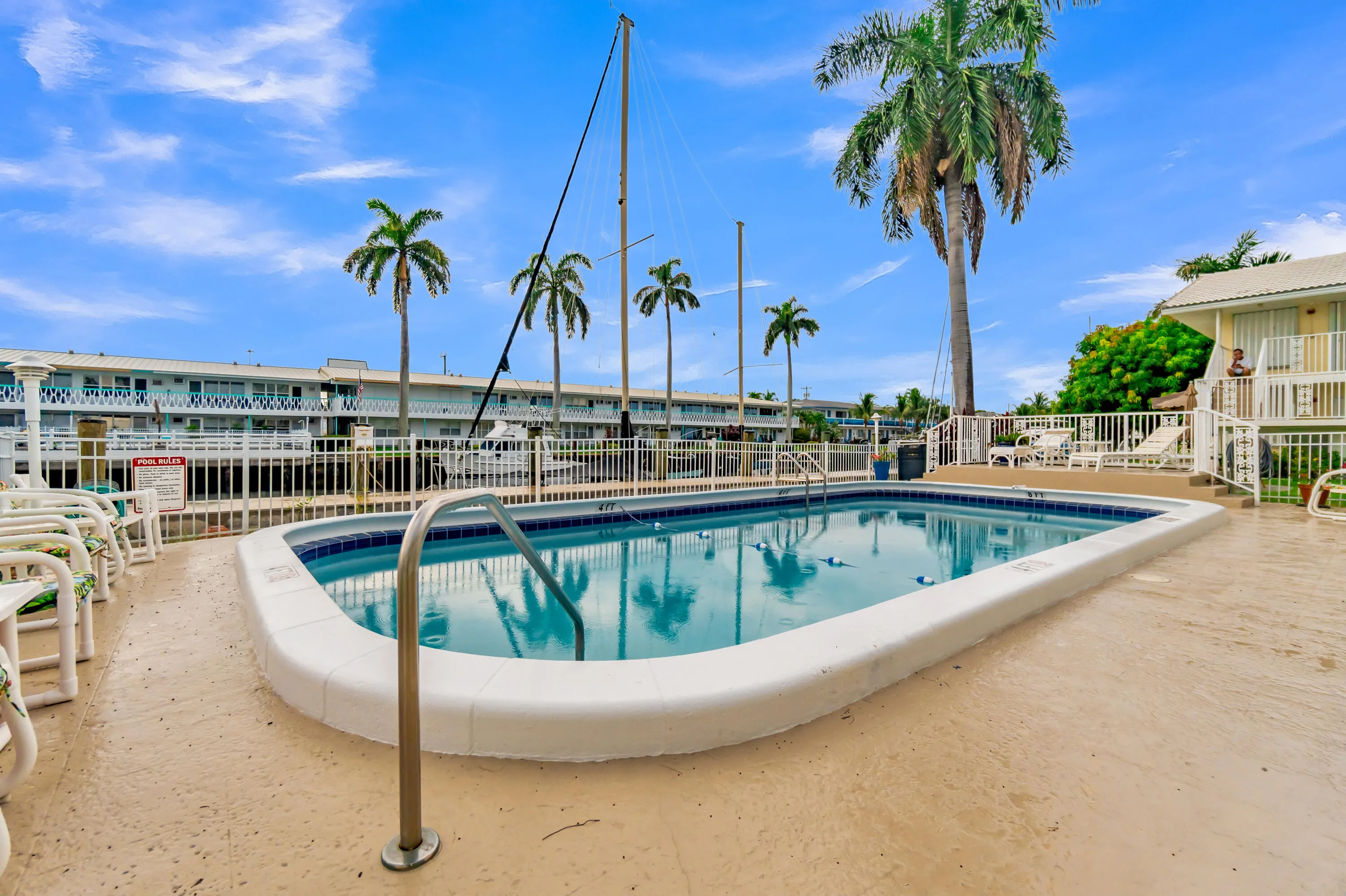 Outdoor swimming pool with integrated steps and handrails, surrounded by a paved deck