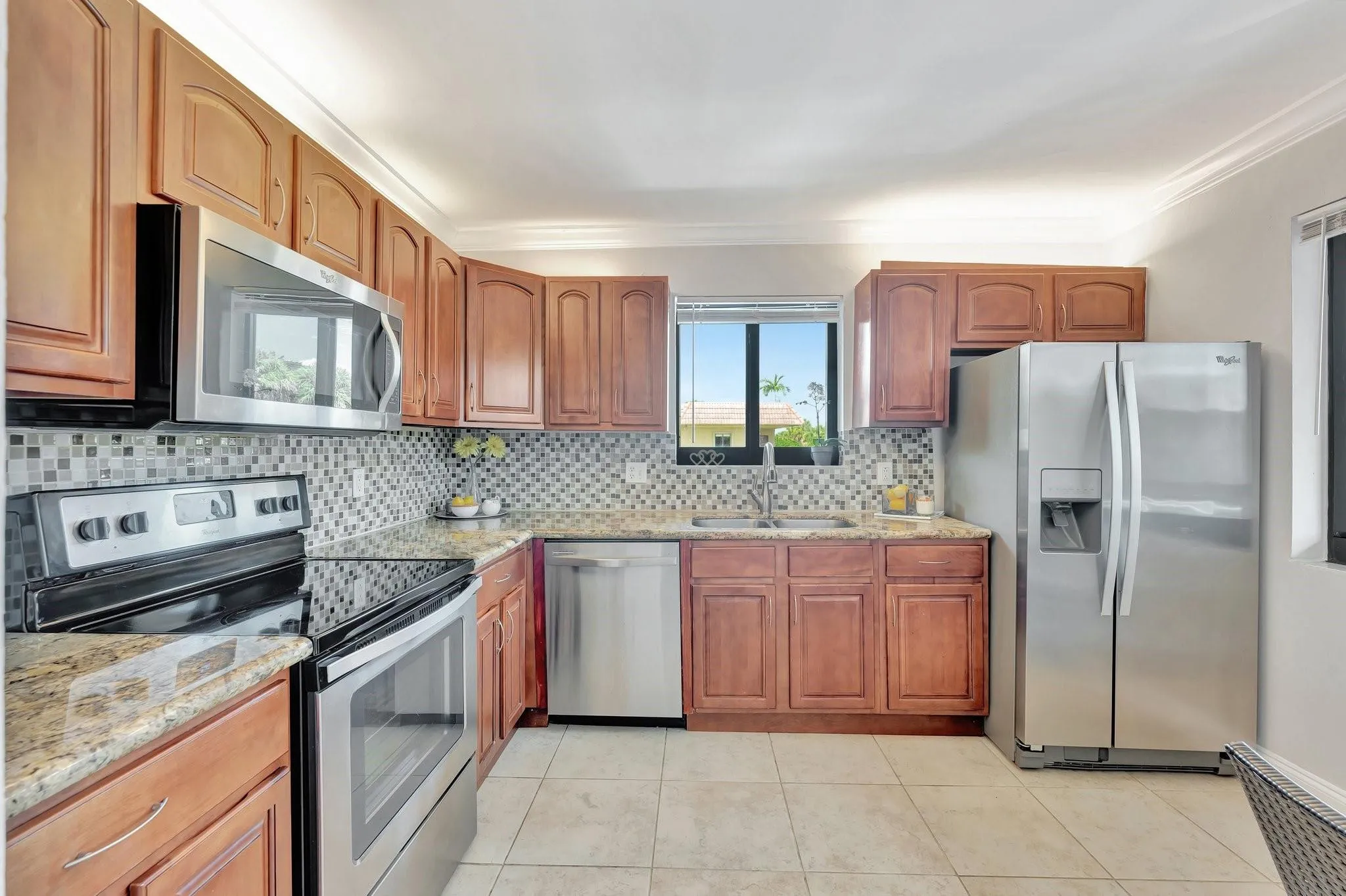 Tiled backsplash, ample wooden cabinetry with built in lighting, stainless appliances.
