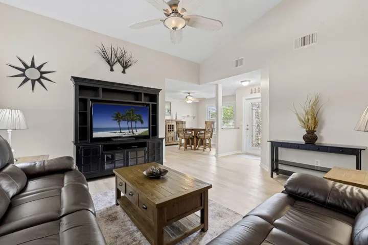Vaulted ceilings, wood-finish flooring, recessed lighting, and a ceiling fan with integrated lighting