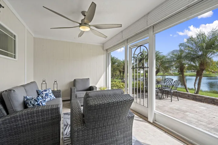 Enclosed patio featuring a ceiling fan, tile flooring, full-height windows, and a glass-paneled door leading to a paver patio