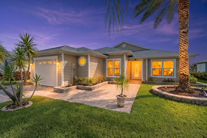Exterior featuring horizontal siding, an attached garage, paver walkway, decorative landscaping, and a pitched roof