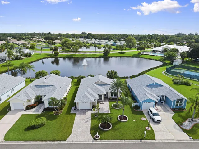 Lakeside residences with manicured lawns, paver driveways, and mature landscaping