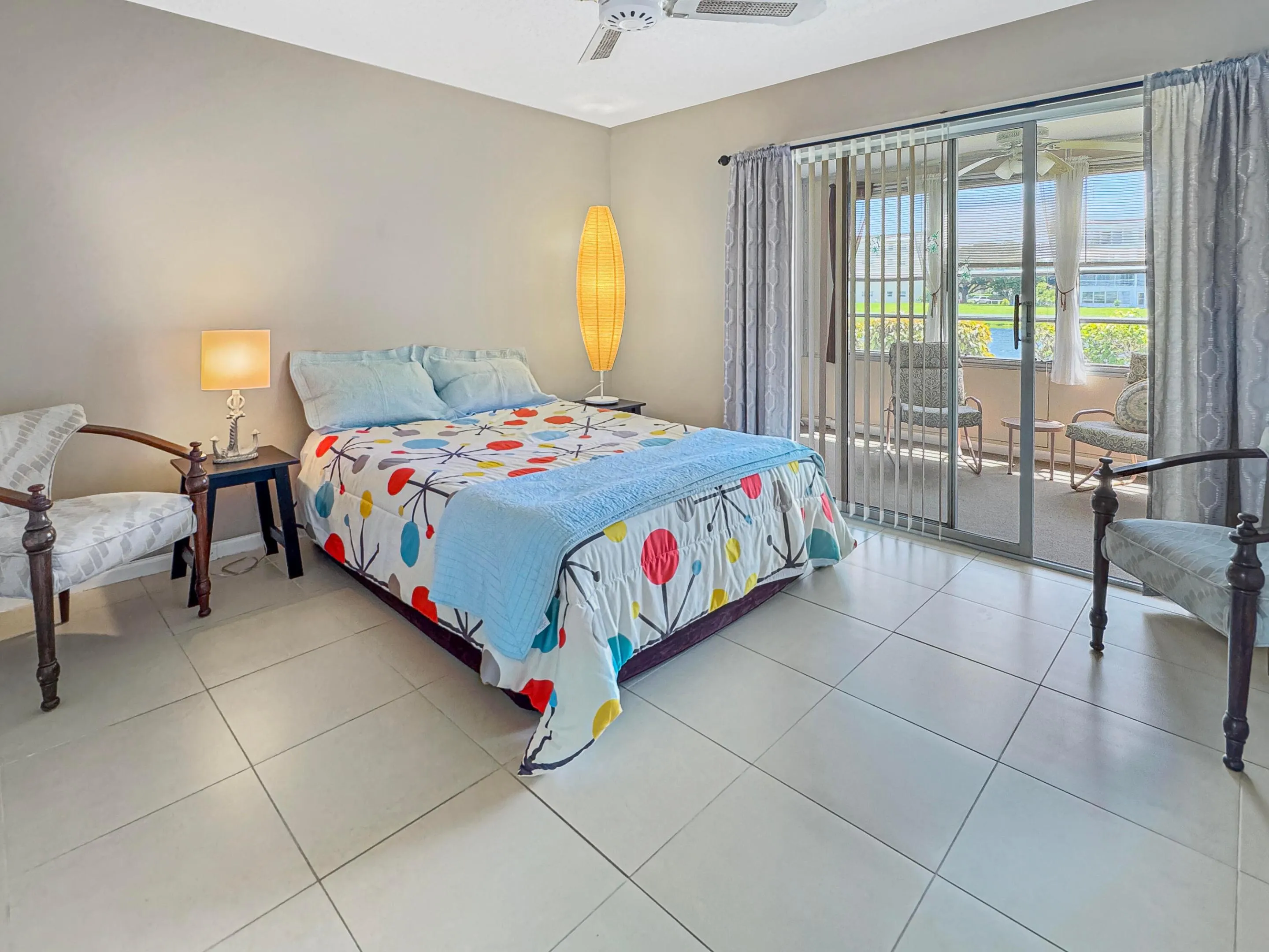 Light-toned tile flooring, ceiling fan, and sliding glass doors leading to a screened-in patio
