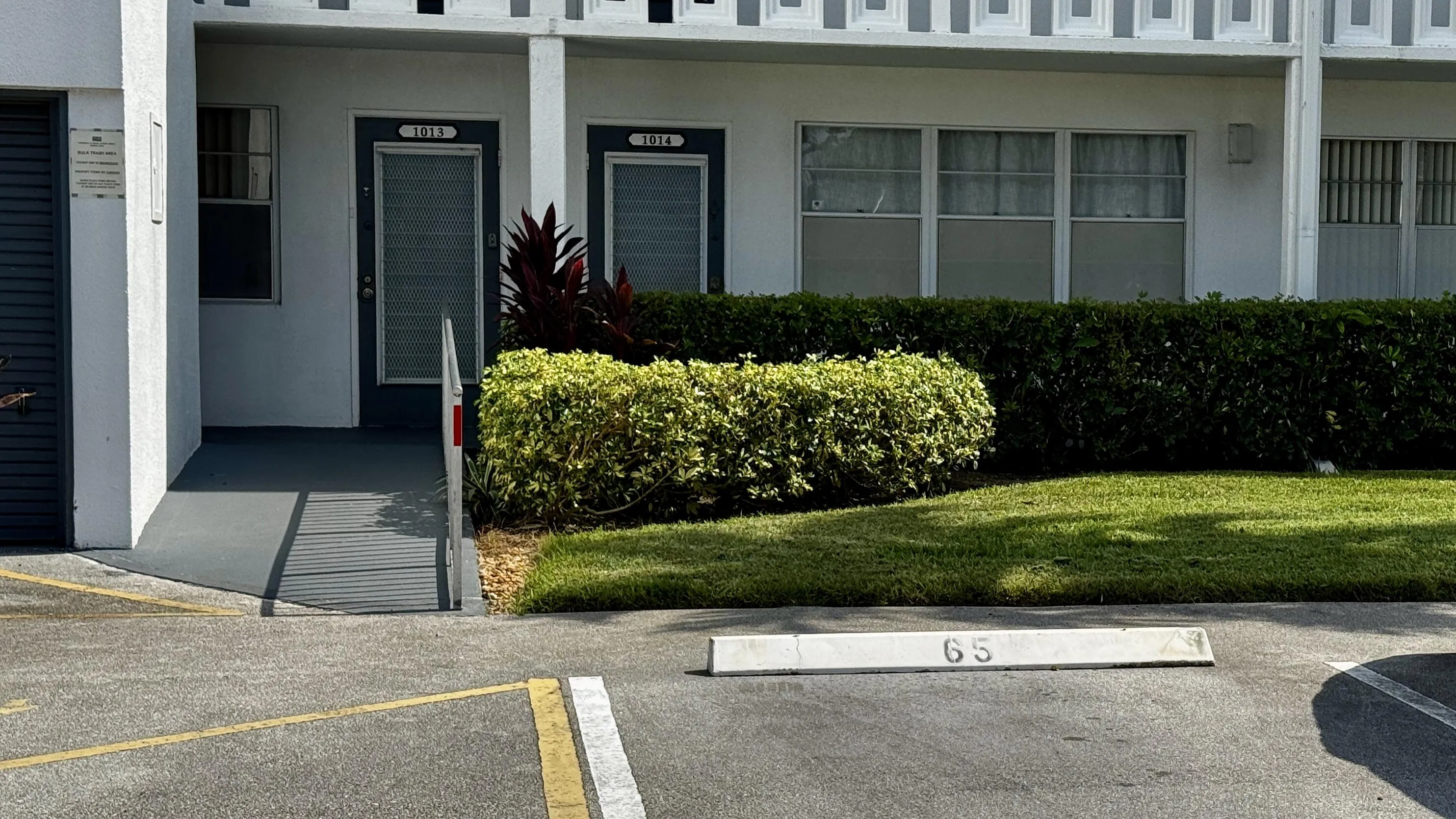 Ground-level unit with ramp access, patterned facade, and a neatly manicured lawn