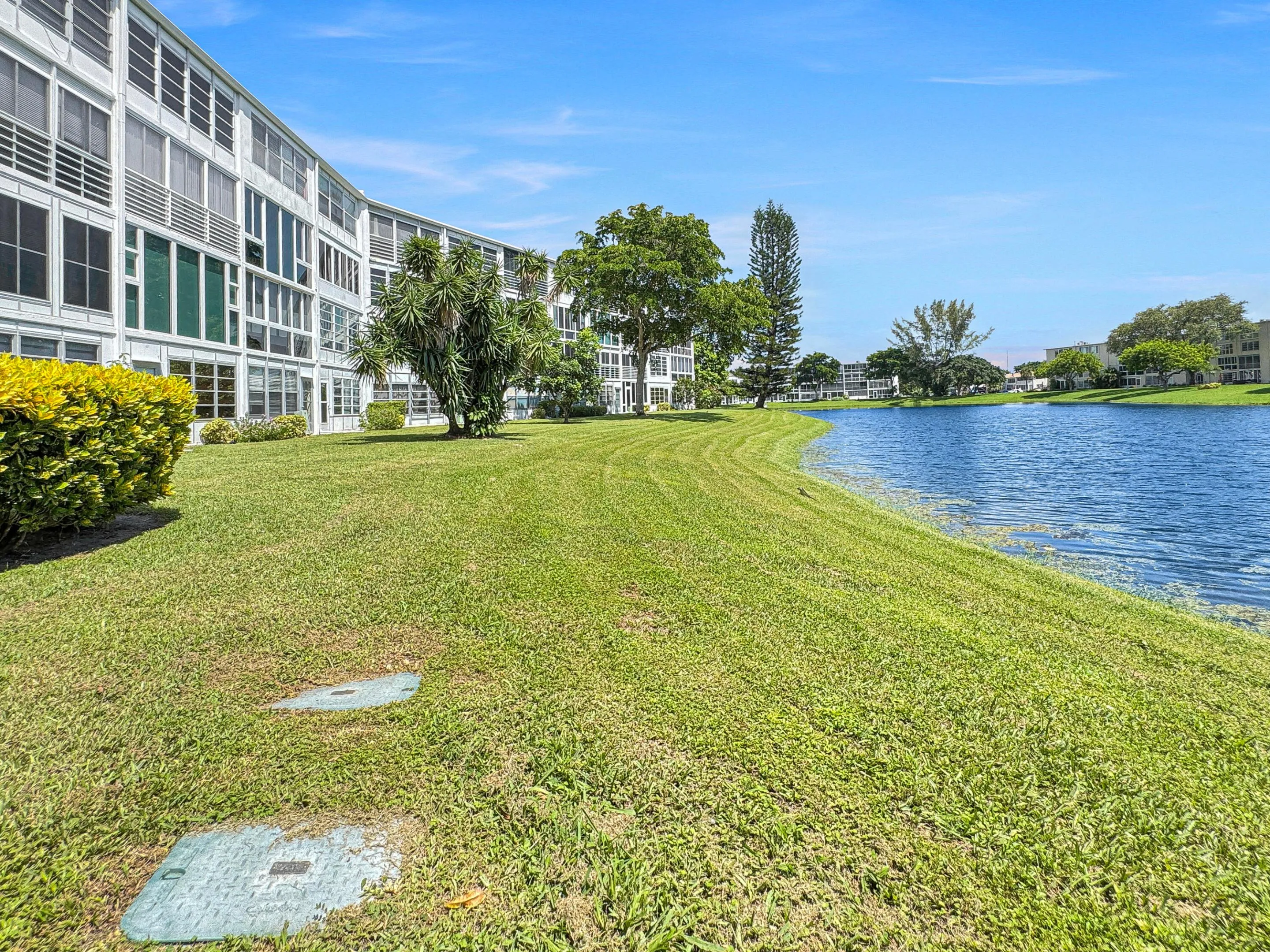 Expansive lawn area with established landscaping, bordering a serene water feature