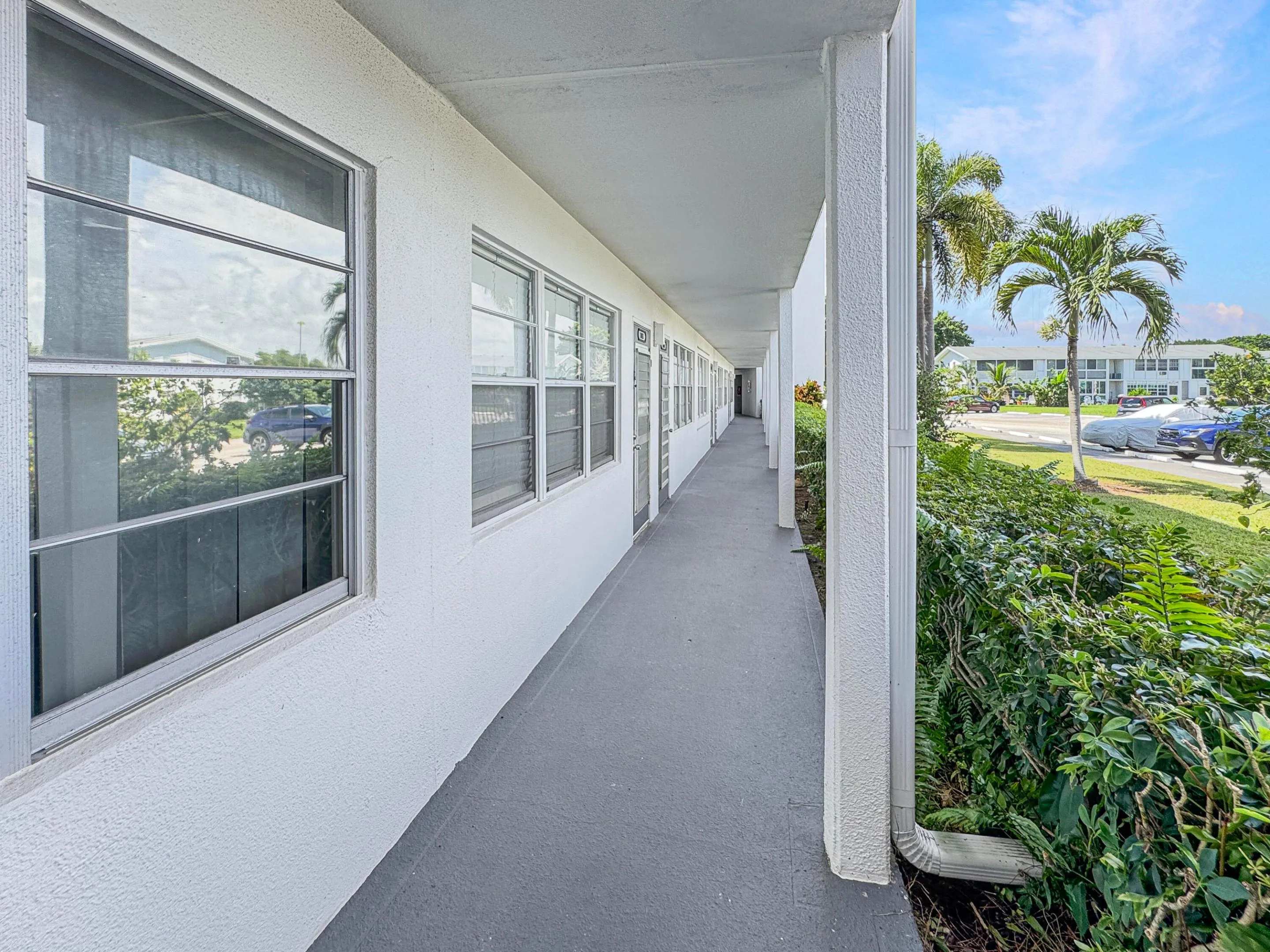 Covered exterior walkway featuring a textured ceiling, smooth flooring, and multiple windows
