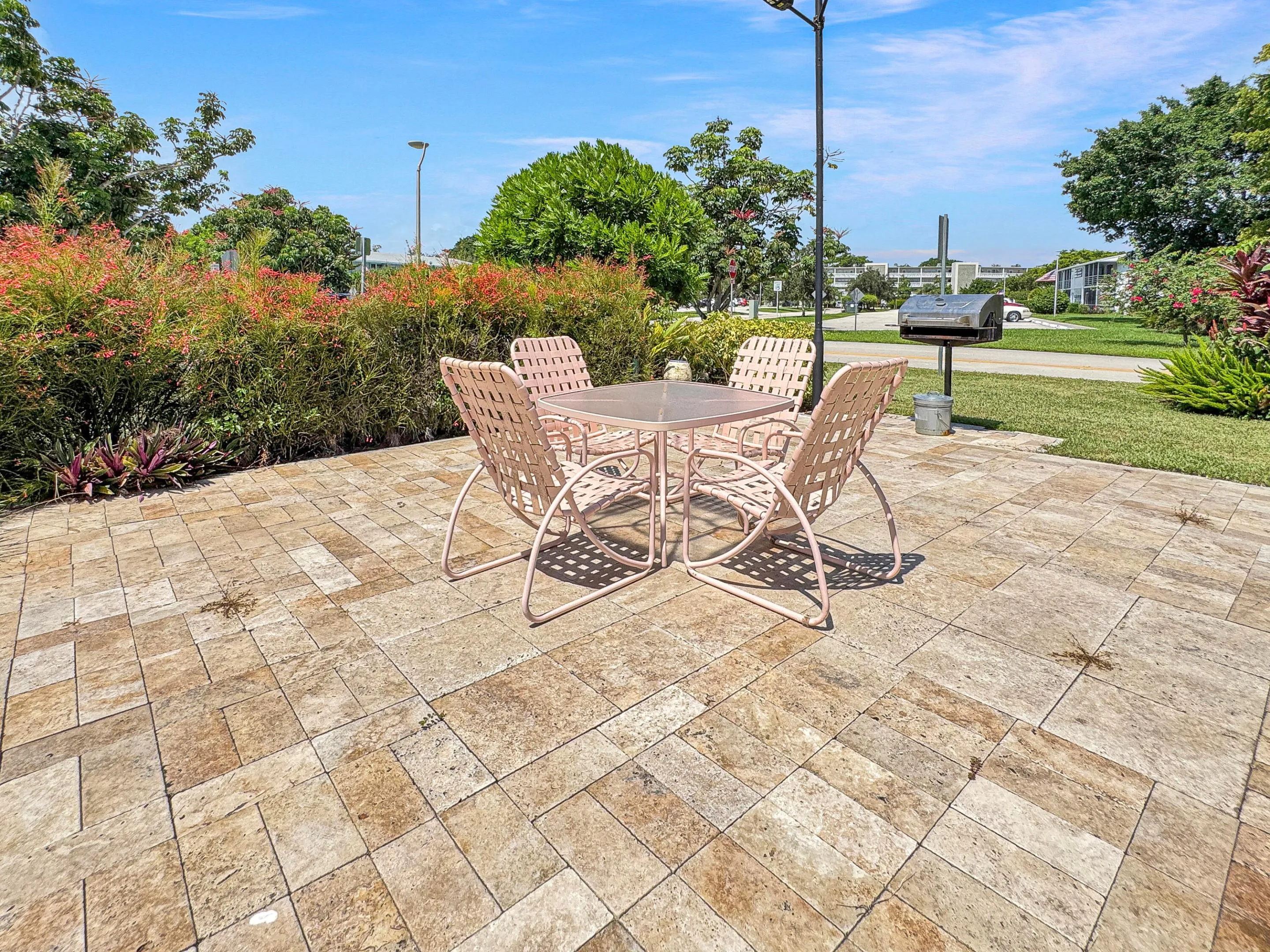 Expansive paver patio with a built-in barbecue grill and surrounding mature landscaping