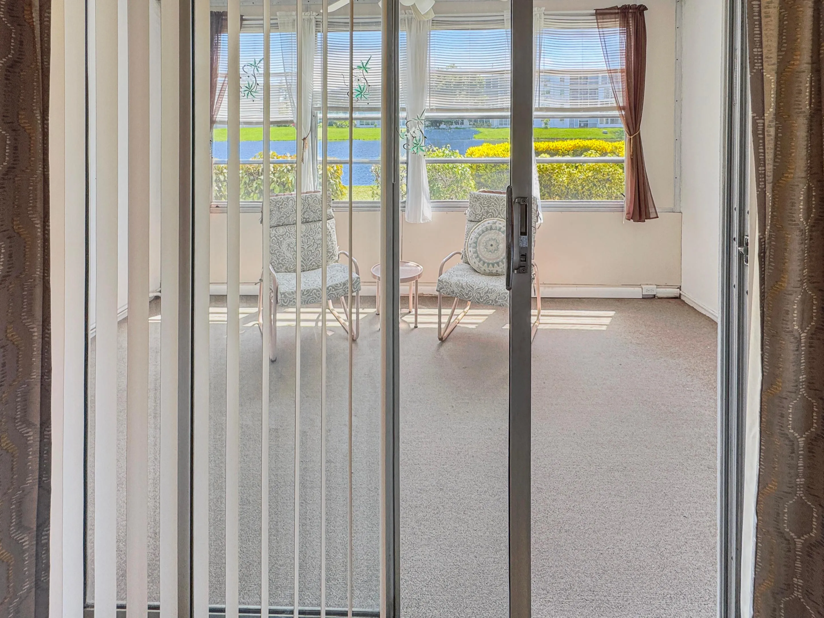 Sliding glass door entry to a sunroom featuring multiple windows and neutral flooring