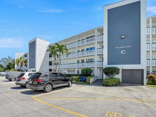 Concrete residential building with multiple balconies, a covered entry, and dedicated parking
