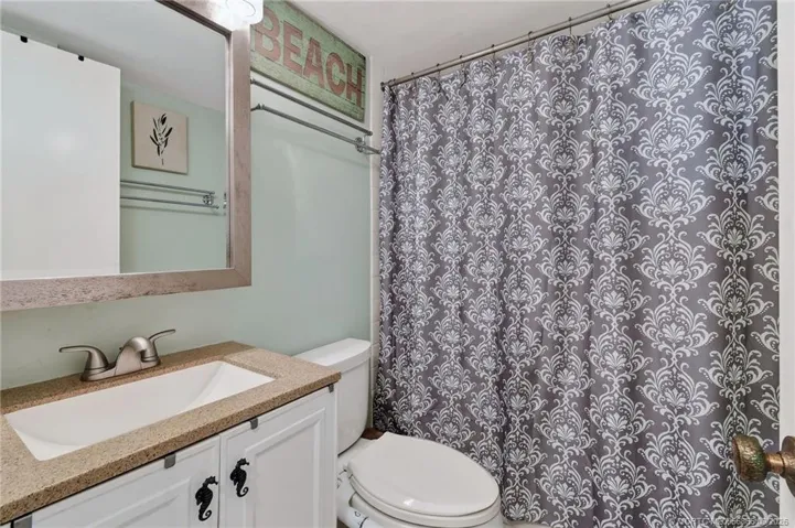 Guest bathroom with updated vanity, stone-look countertop and tub/shower combination.