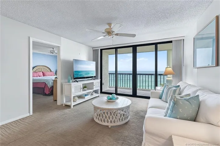 Living room with expansive glass doors framing beautiful direct ocean views and access to the private balcony. Virtually staged.