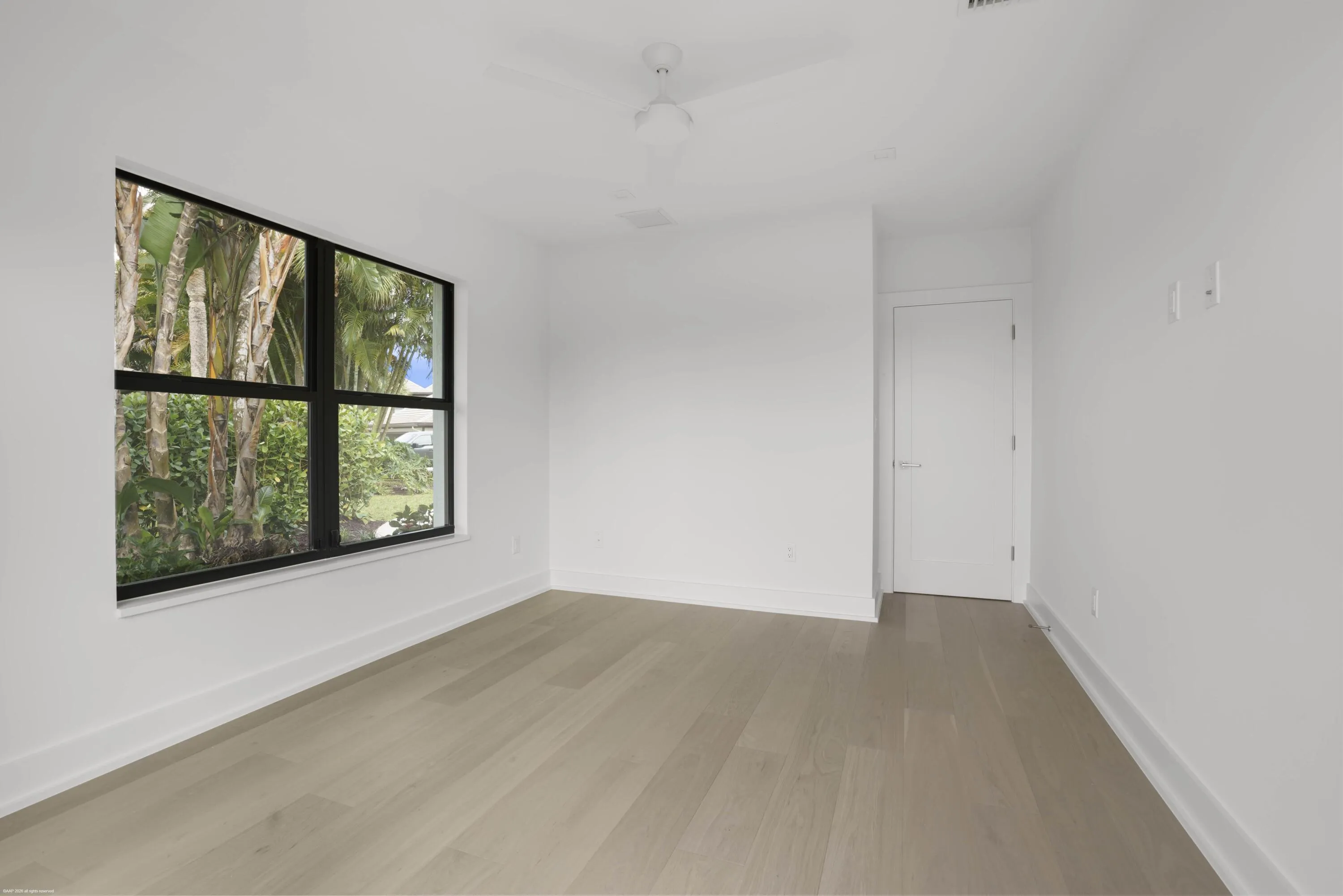 Expansive window with black framing, wood-finish flooring, white walls, and a ceiling fan