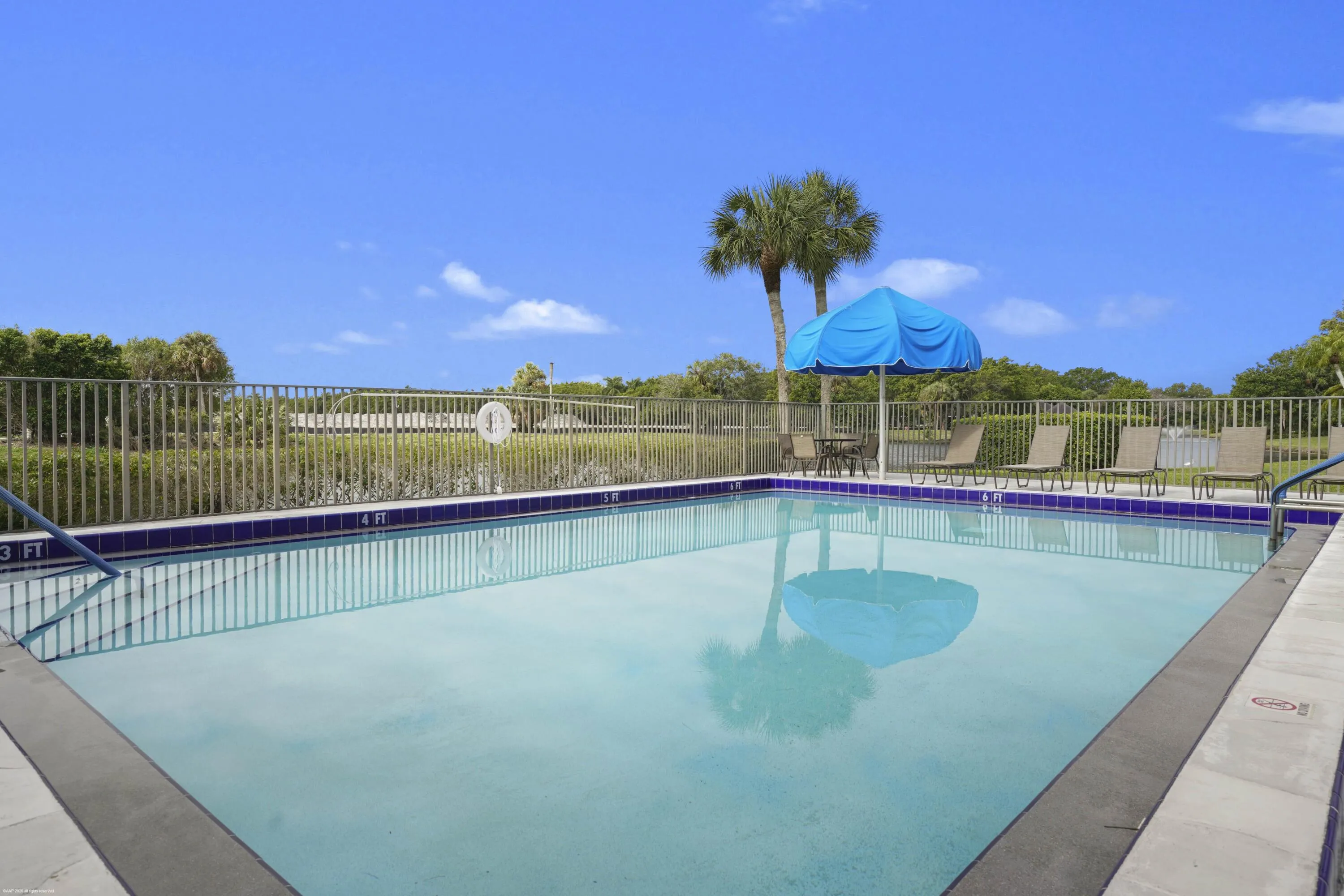 Swimming pool with integrated steps, tile border, and adjacent fencing