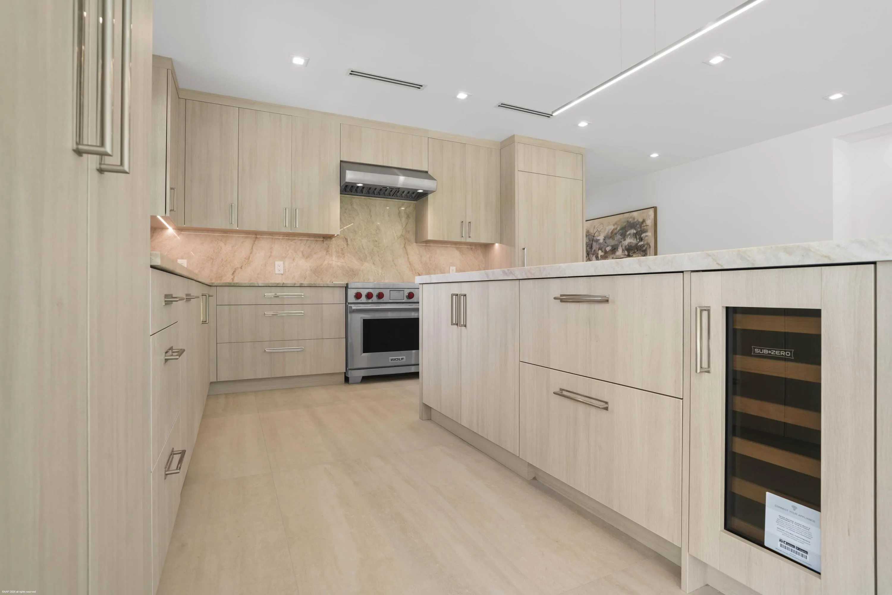 Light wood-finish cabinetry with silver-tone pulls, stone countertops with matching backsplash, stainless steel range with hood, integrated wine refrigerator, and light wood-finish flooring
