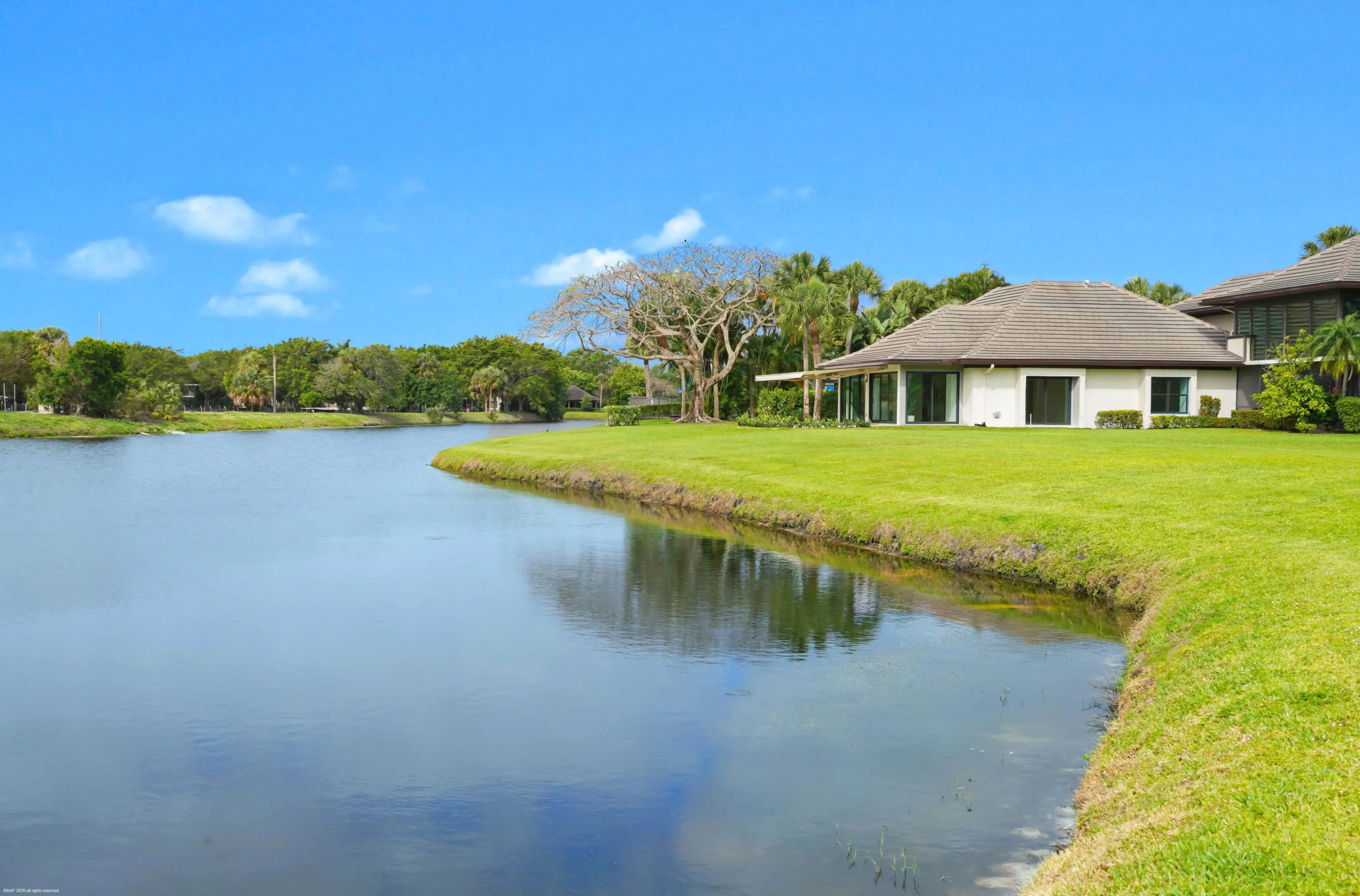 Waterfront property featuring a well-maintained lawn and mature landscaping