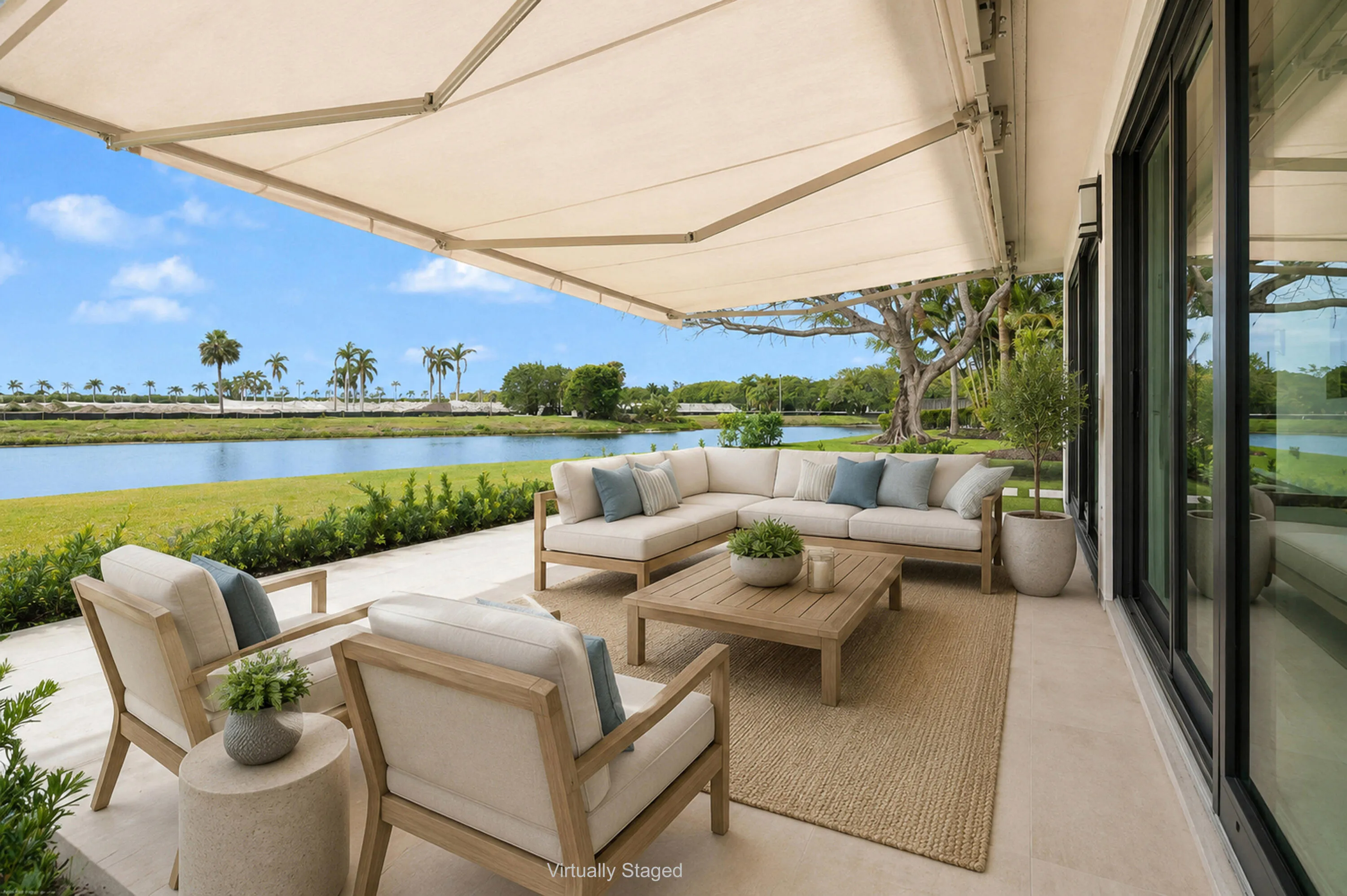 Expansive outdoor patio with retractable awning, large format tile flooring, and sliding glass doors