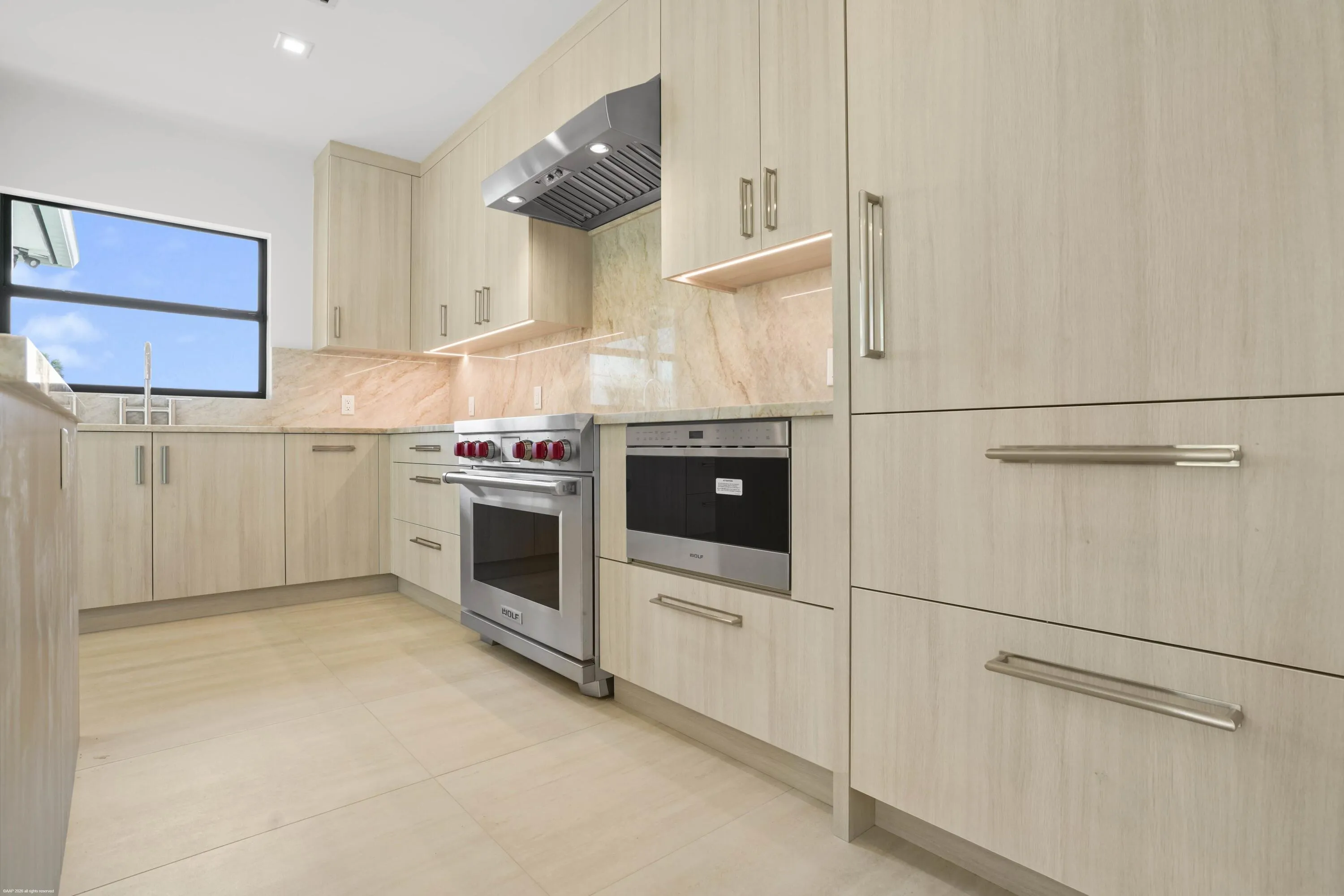 Full-height cabinetry with integrated appliances, stainless steel range with matching hood, stone countertops with backsplash, and recessed lighting