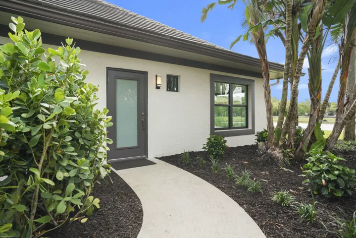 Textured exterior with dark trim, frosted-glass entry door, and exterior sconce lighting