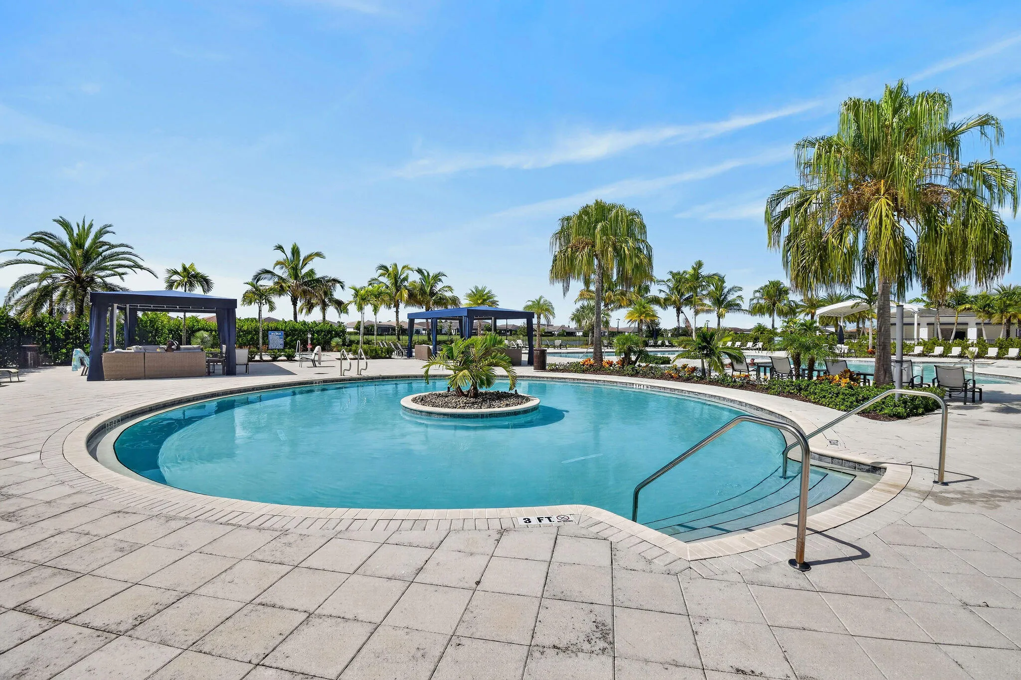 Circular swimming pool with integrated steps, surrounded by stone pavers, lush landscaping, and multiple pergolas