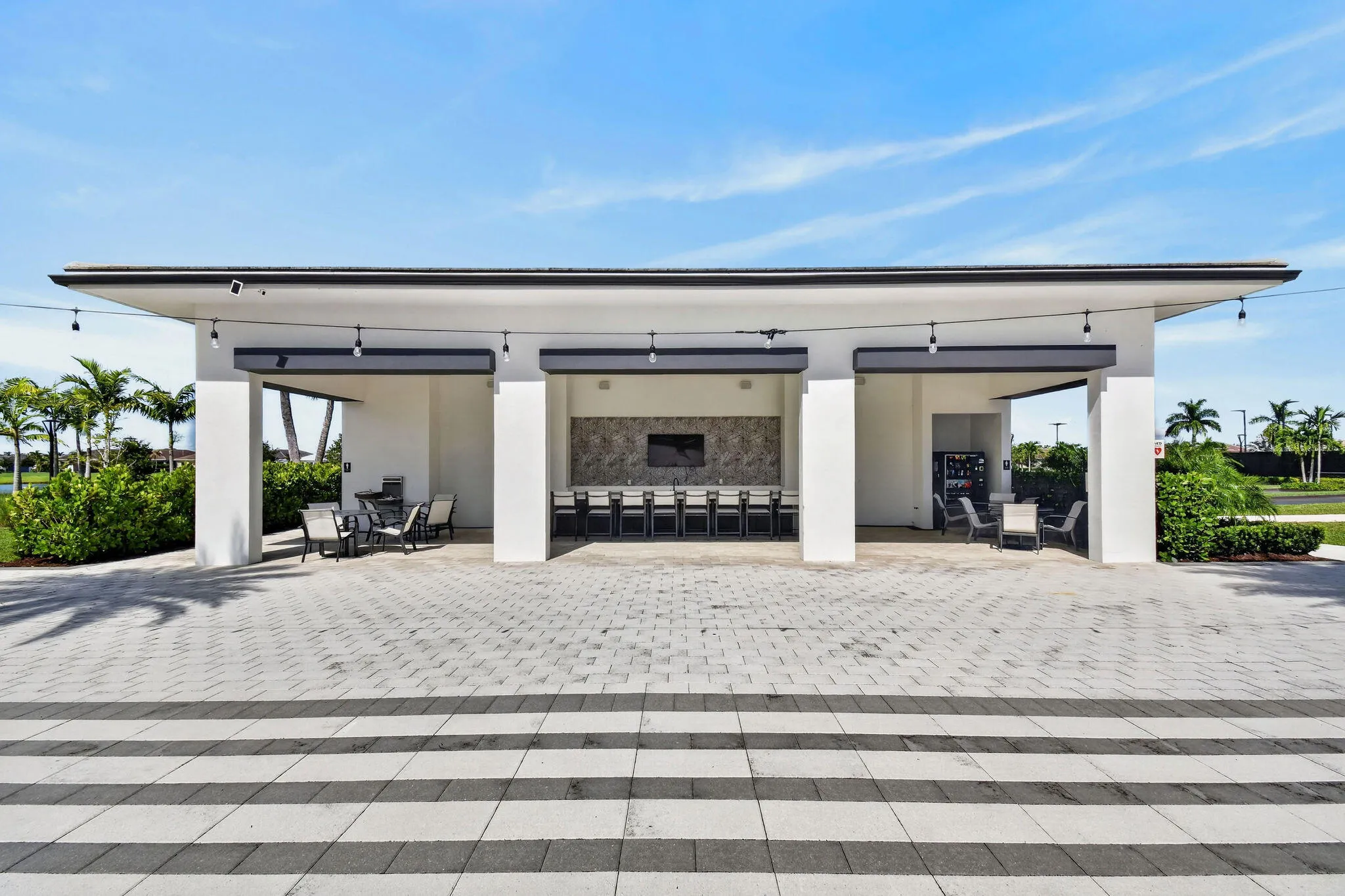 Expansive outdoor structure featuring a covered dining area, built-in grill, and a stone-finish accent wall