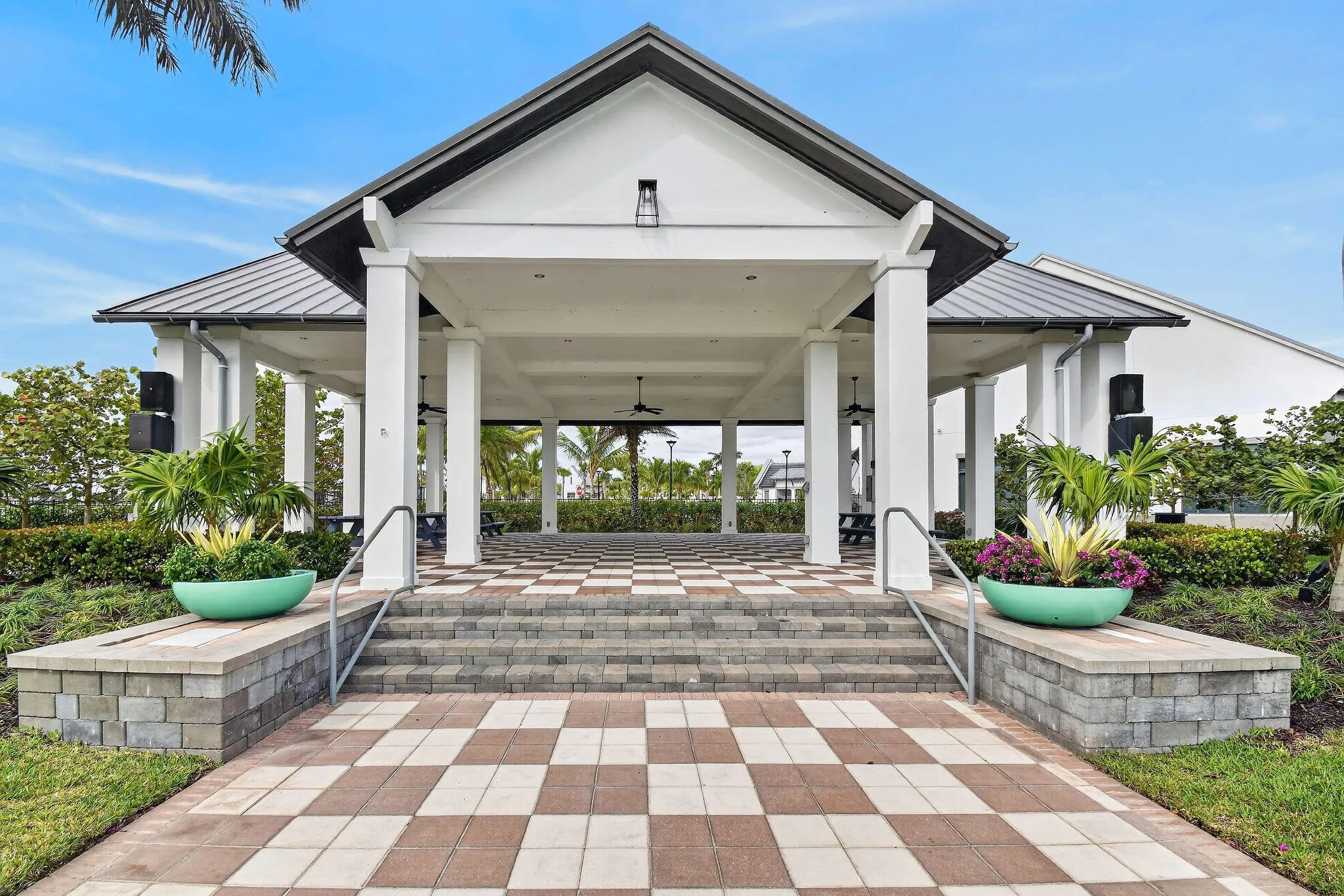Expansive covered patio featuring a gabled roofline, checkerboard paver flooring, and multiple support columns