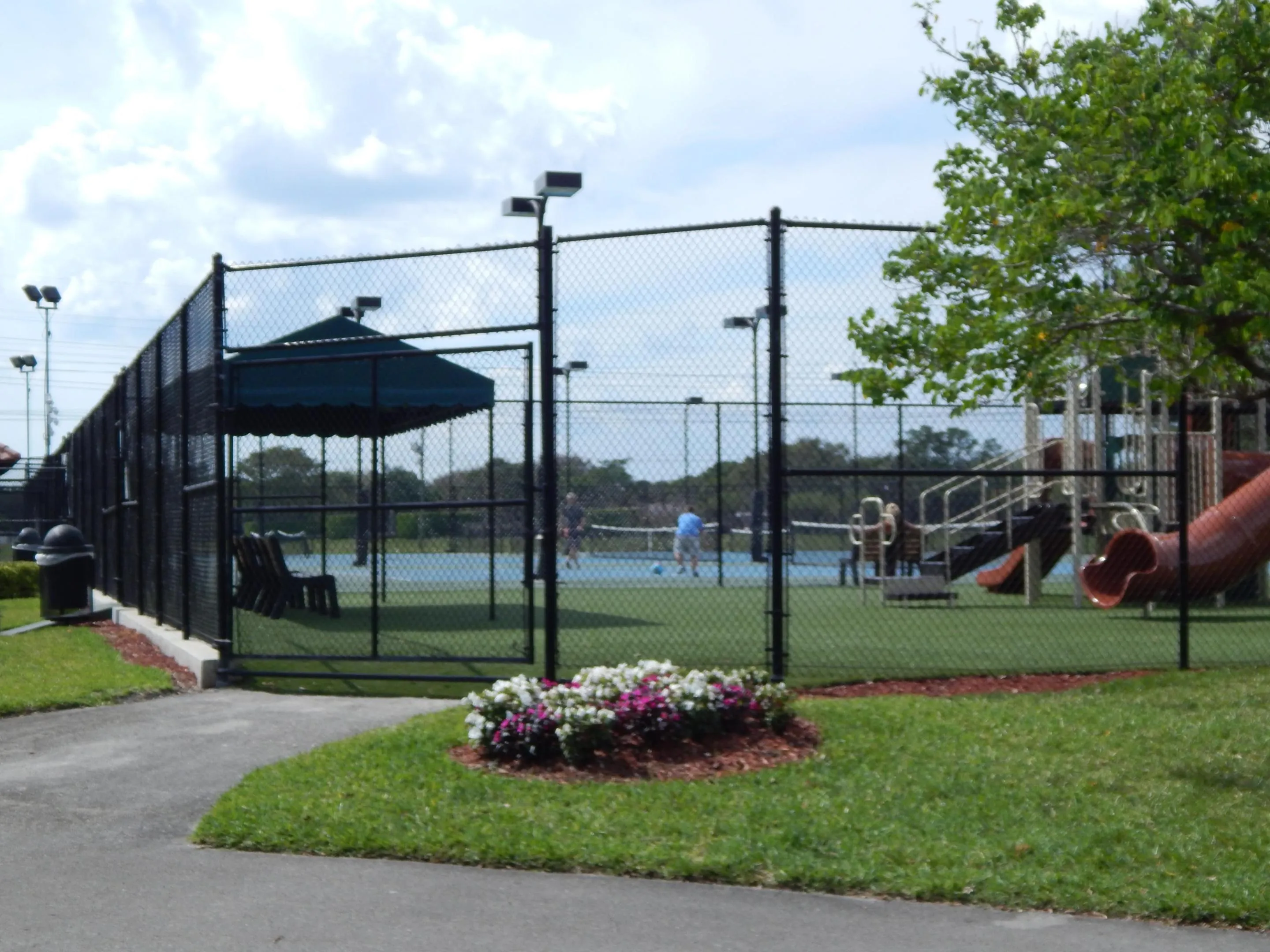 Tennis courts with perimeter fencing and overhead lighting