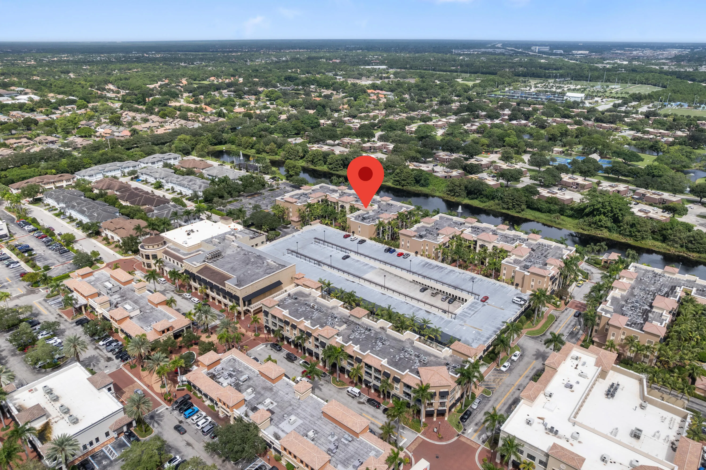 Aerial perspective of a multi-story building featuring a central parking structure, surrounded by additional multi-story structures