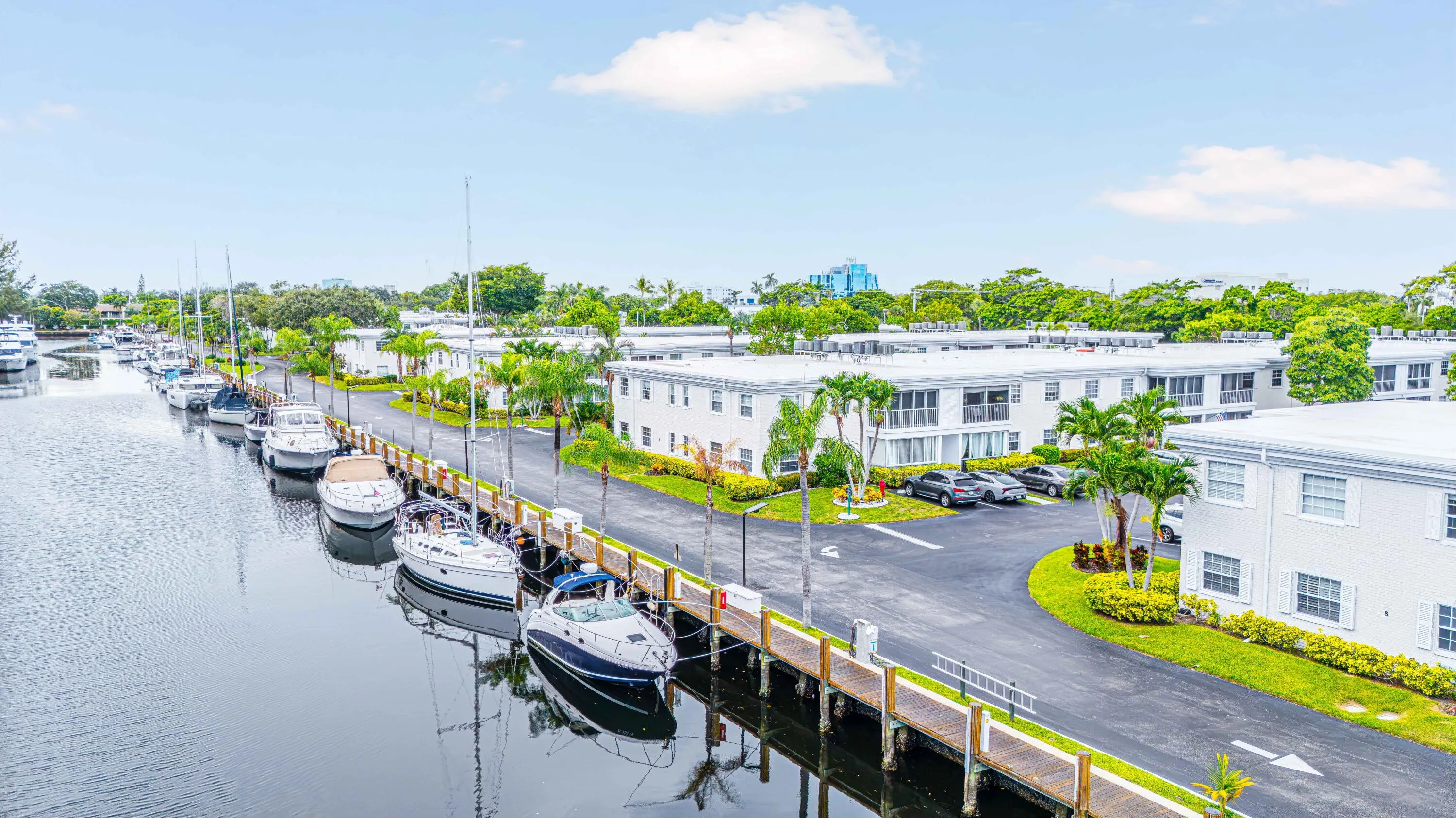 Waterfront property featuring a private dock, tropical landscaping, and a paved parking area