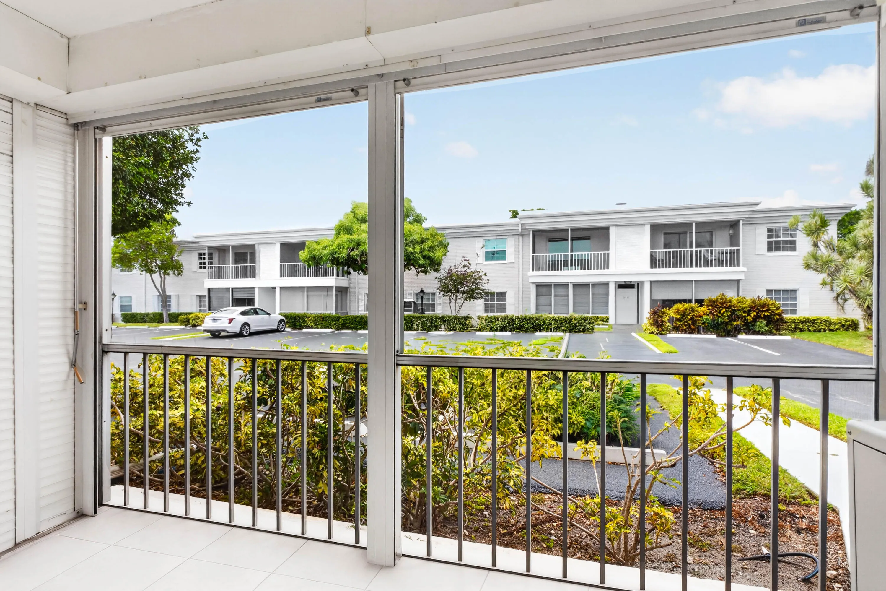 Screened balcony with white tile flooring and metal railings